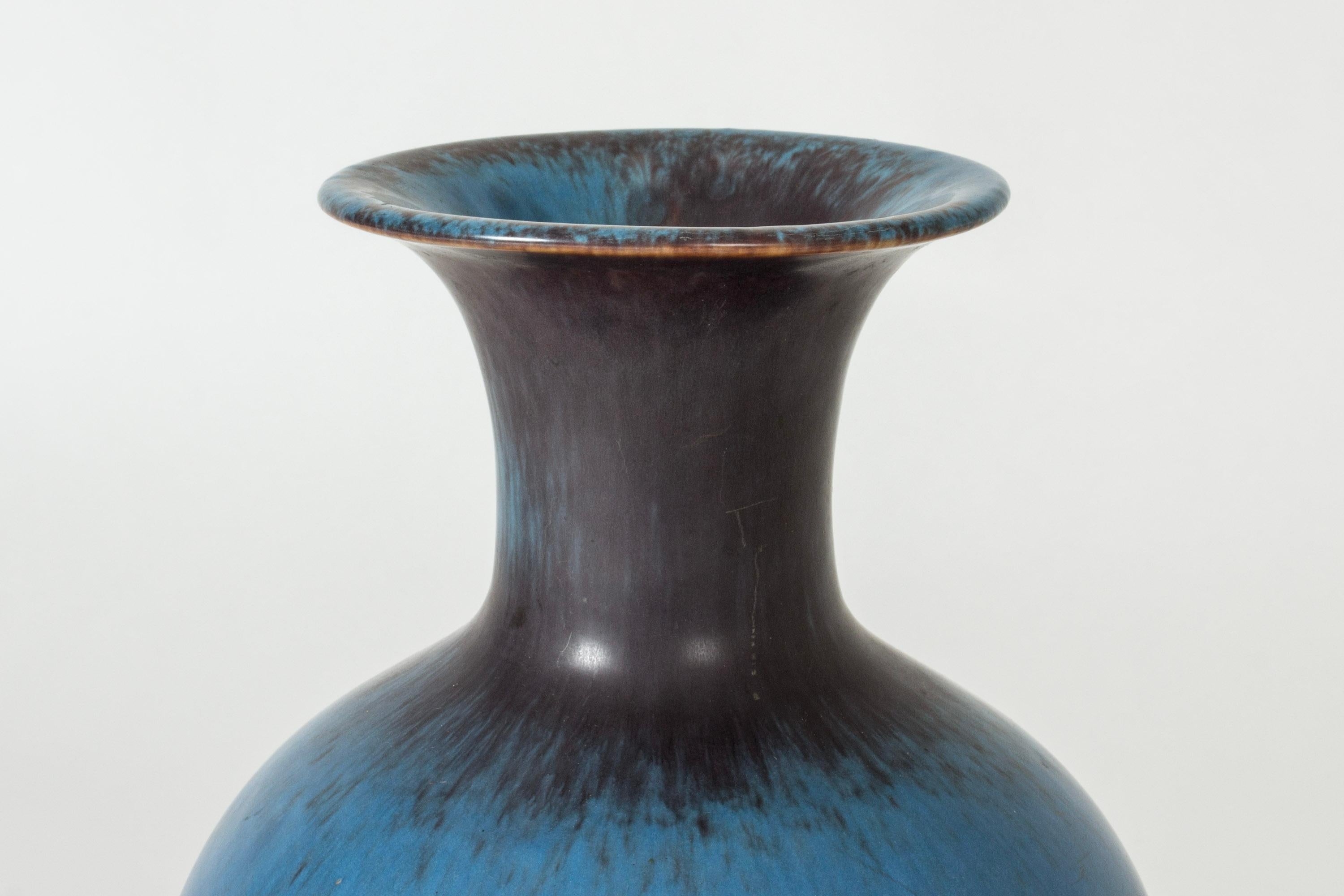Large stoneware floor vase by Gunnar Nylund in a classic shape. Beautiful glaze that alternates between purple and clear blue in dramatic splashes.