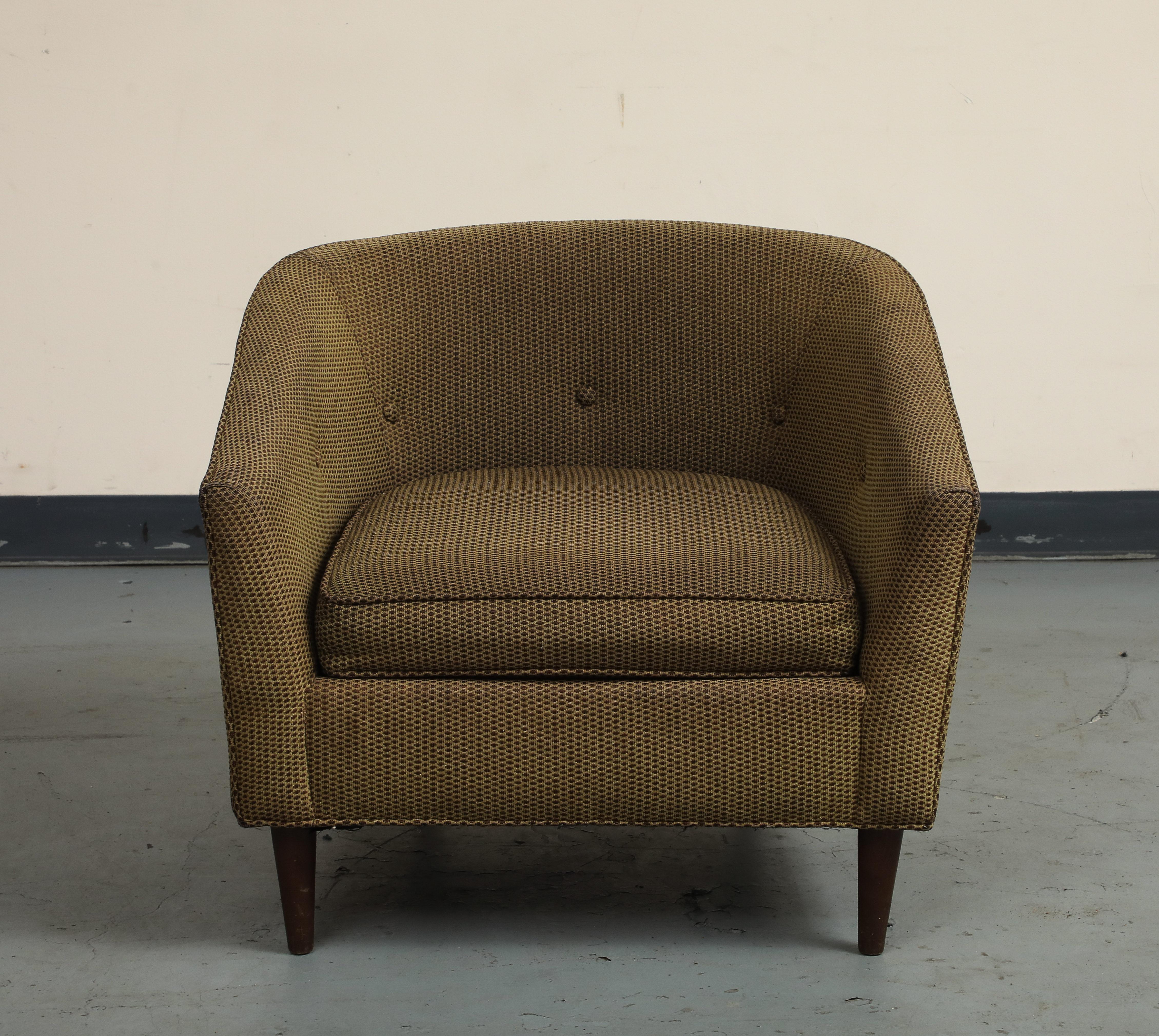 A classic vintage midcentury style Italian lounge chair. The chair is upholstered in a textured fabric with a subtle pattern, complemented by its elegant, curved armrests and tapered wooden legs. Upholstered buttons accent the back rest. The seat