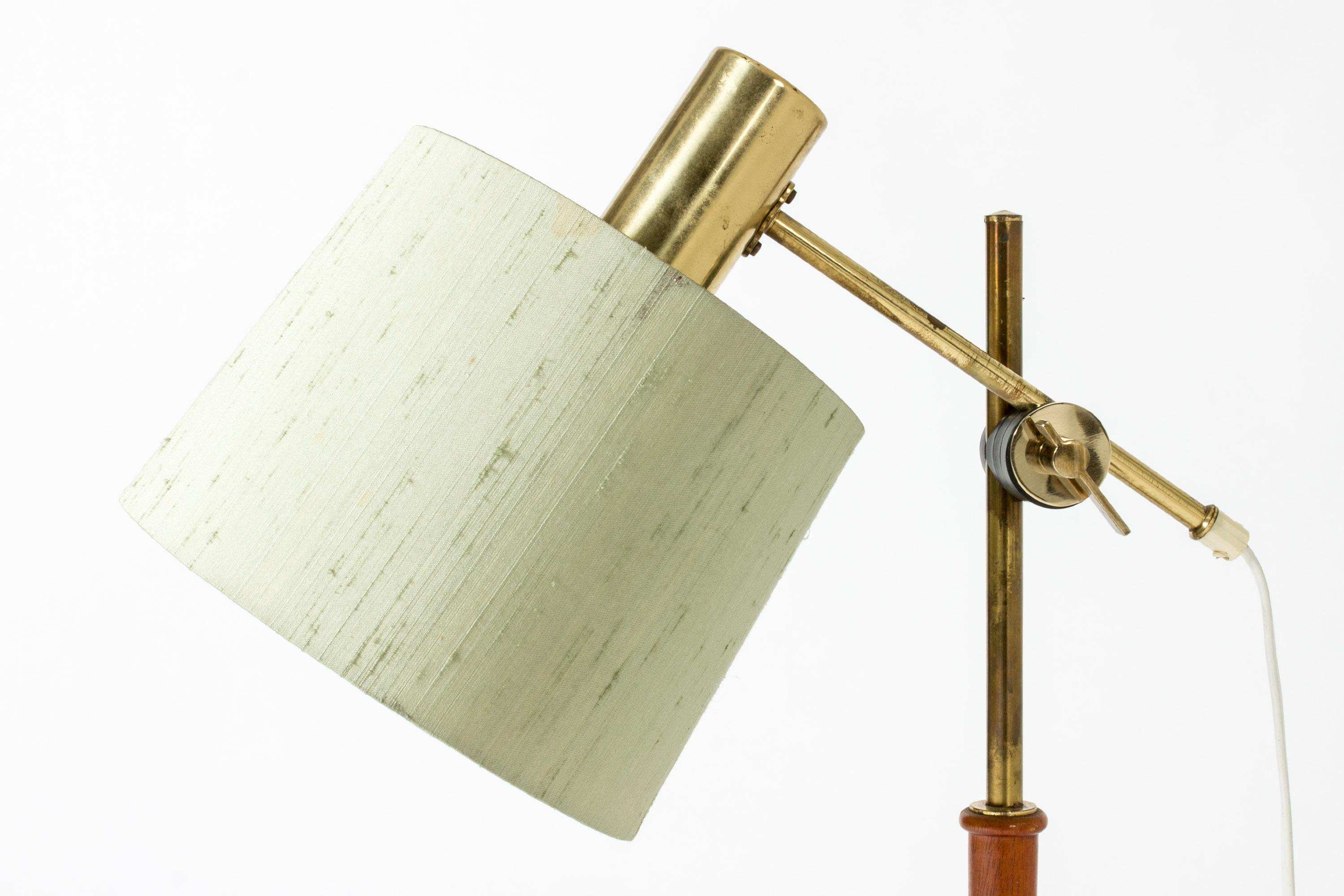 Cool table lamp from Falkenbergs Belysning, made from brass with a teak stem. Wood carved into a bamboo-stem form. Adjustable height and angle of the shade. Original silk shade.