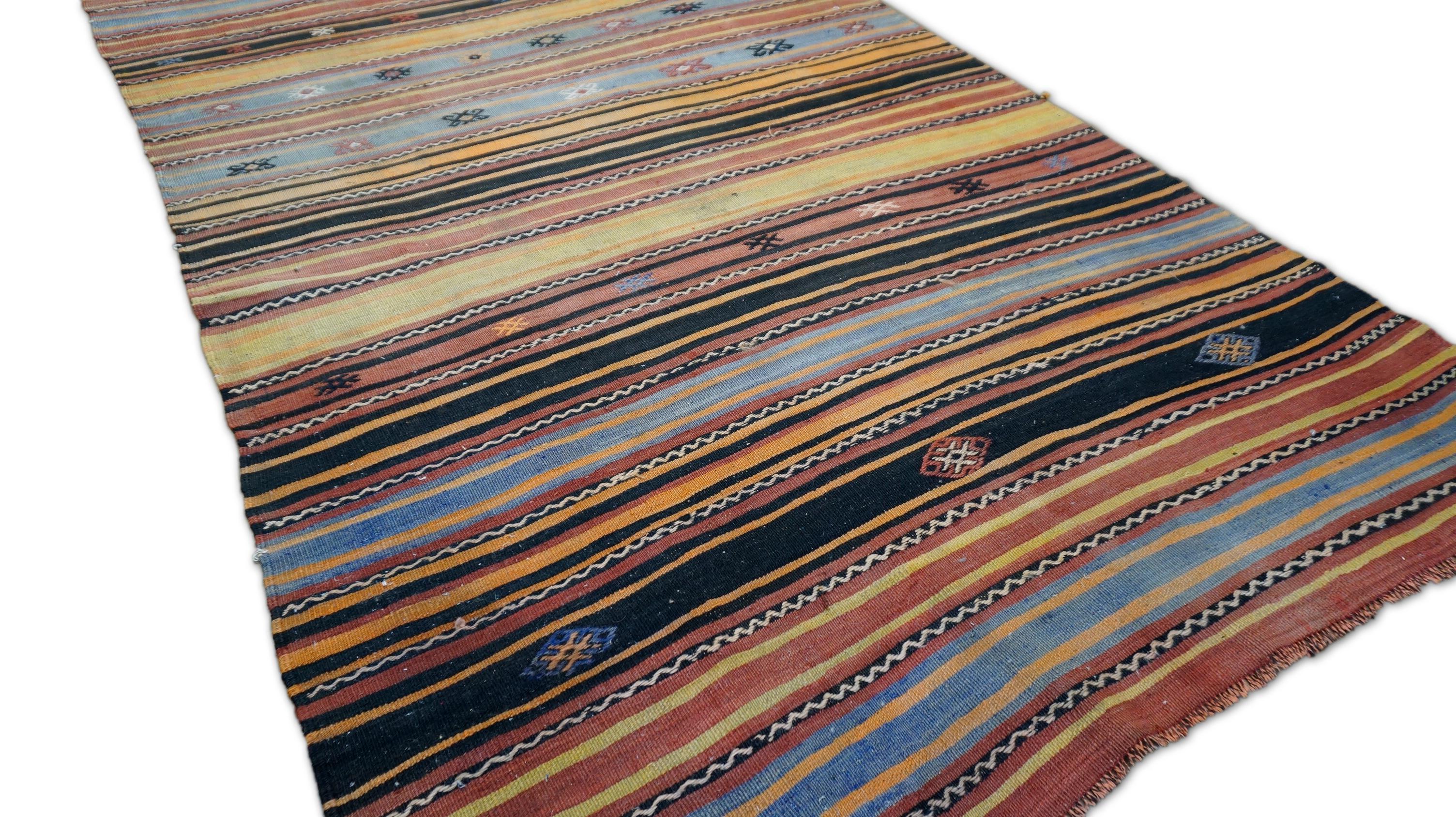 This handwoven kilim is a striking example of nomadic textile art, showcasing a classic horizontal stripe format interspersed with symbolic tribal motifs. Woven in the early-20th century using hand-spun wool and natural vegetable dyes, this piece