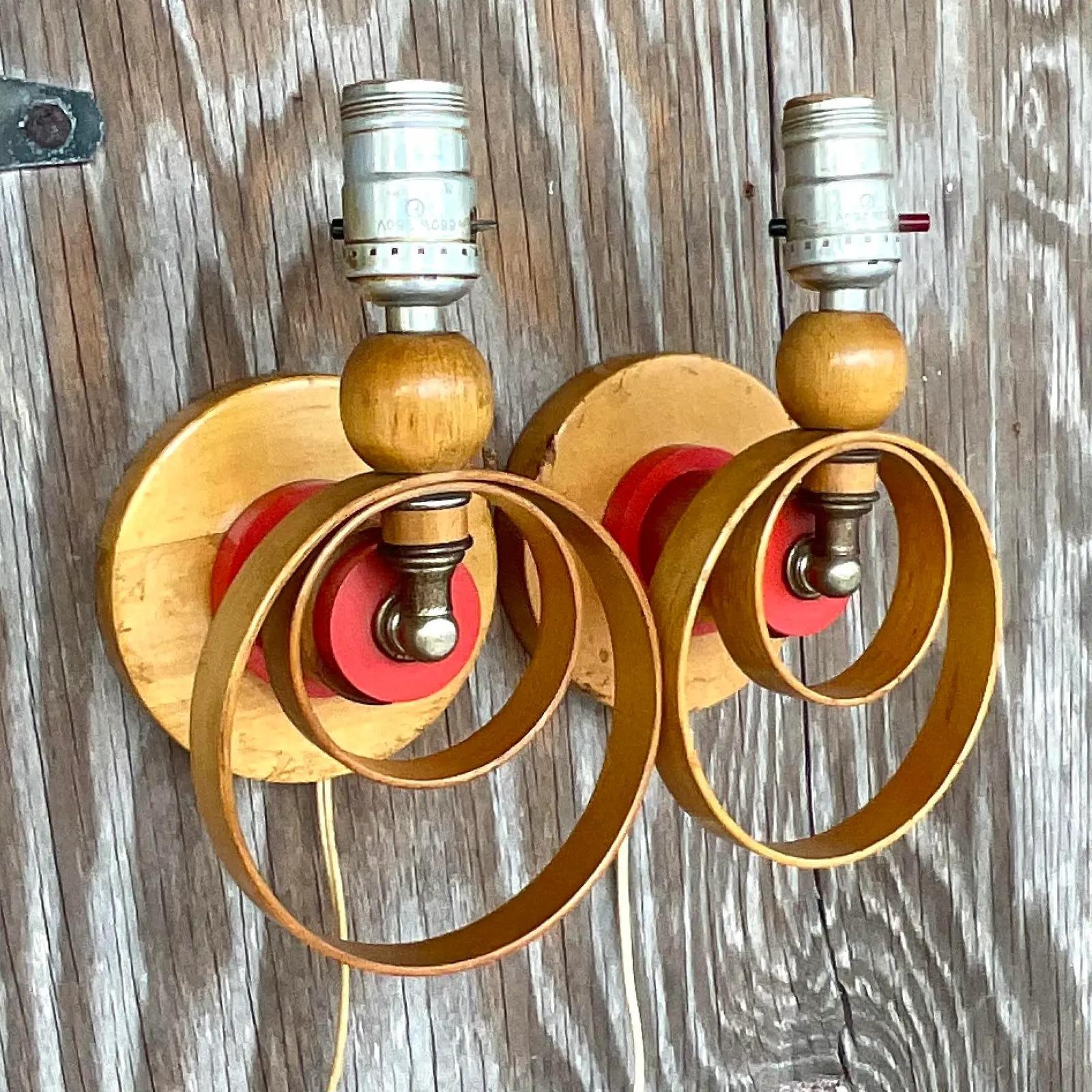 An incredible pair of vintage MCM wall sconces. The most amazing ring design with bright flashes of red. Hardwired to plug into the wall. All the great patina from time. Acquired from a Palm Beach estate.