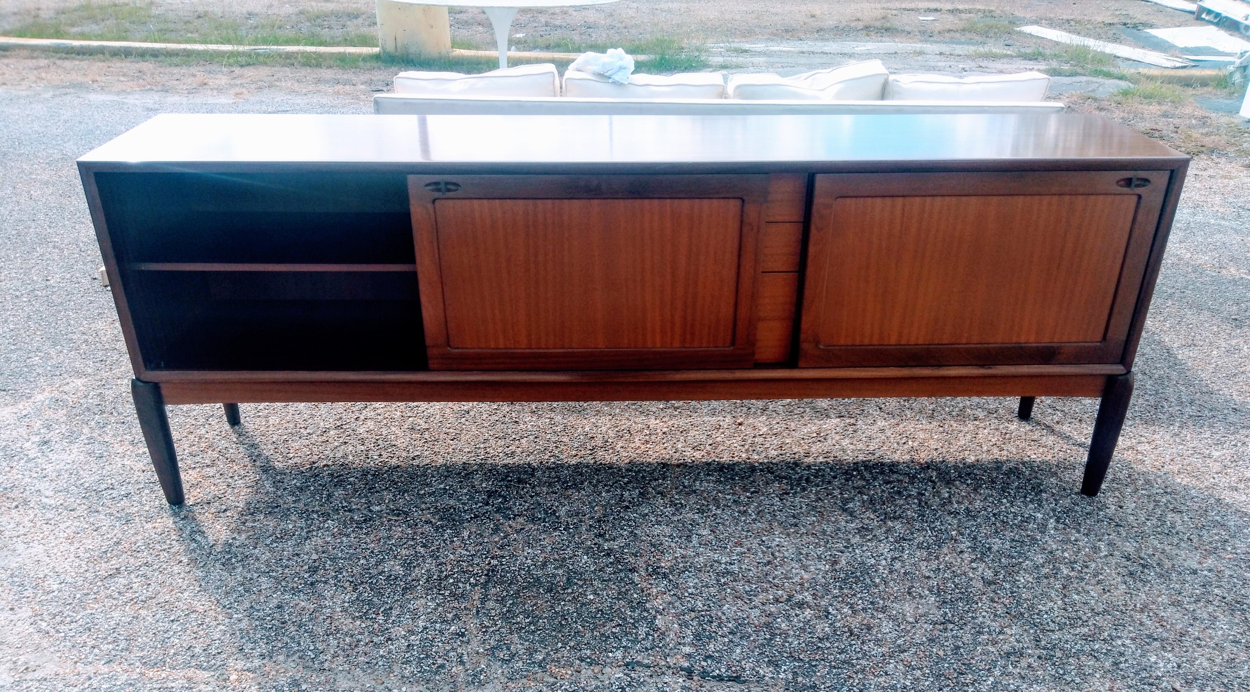 Questa è una credenza vintage a nastro in mogano del Mid Century Mobler di 89 pollici. La credenza è dotata di ante scorrevoli dietro le quali si trova un vano portaoggetti. Ha anche 4 cassetti al centro. La superficie è un ricco nastro di mogano.