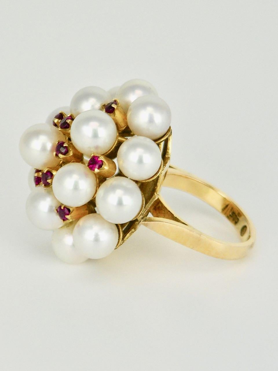 A playful large vintage cocktail ring of 16 pearls arranged in a dome shape with 12 high quality rubies claw set between above a 14k yellow gold fretted star shape basket on a flat shank -  Mikimoto is famous for its high quality classic designs and