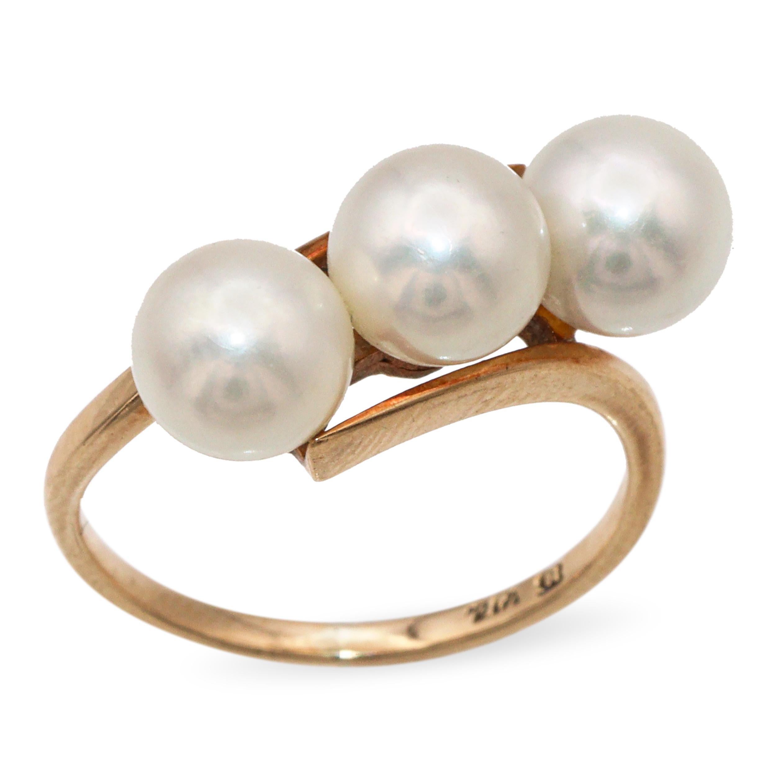 Dieser elegante Vintage-Ring von Mikimoto besteht aus drei glänzenden 6,5 mm Akoya-Perlen, die in 14-karätigem Gelbgold gefasst sind. Mikimoto-Perlen sind für ihre außergewöhnliche Qualität und ihren strahlenden Glanz bekannt und gehören zu den