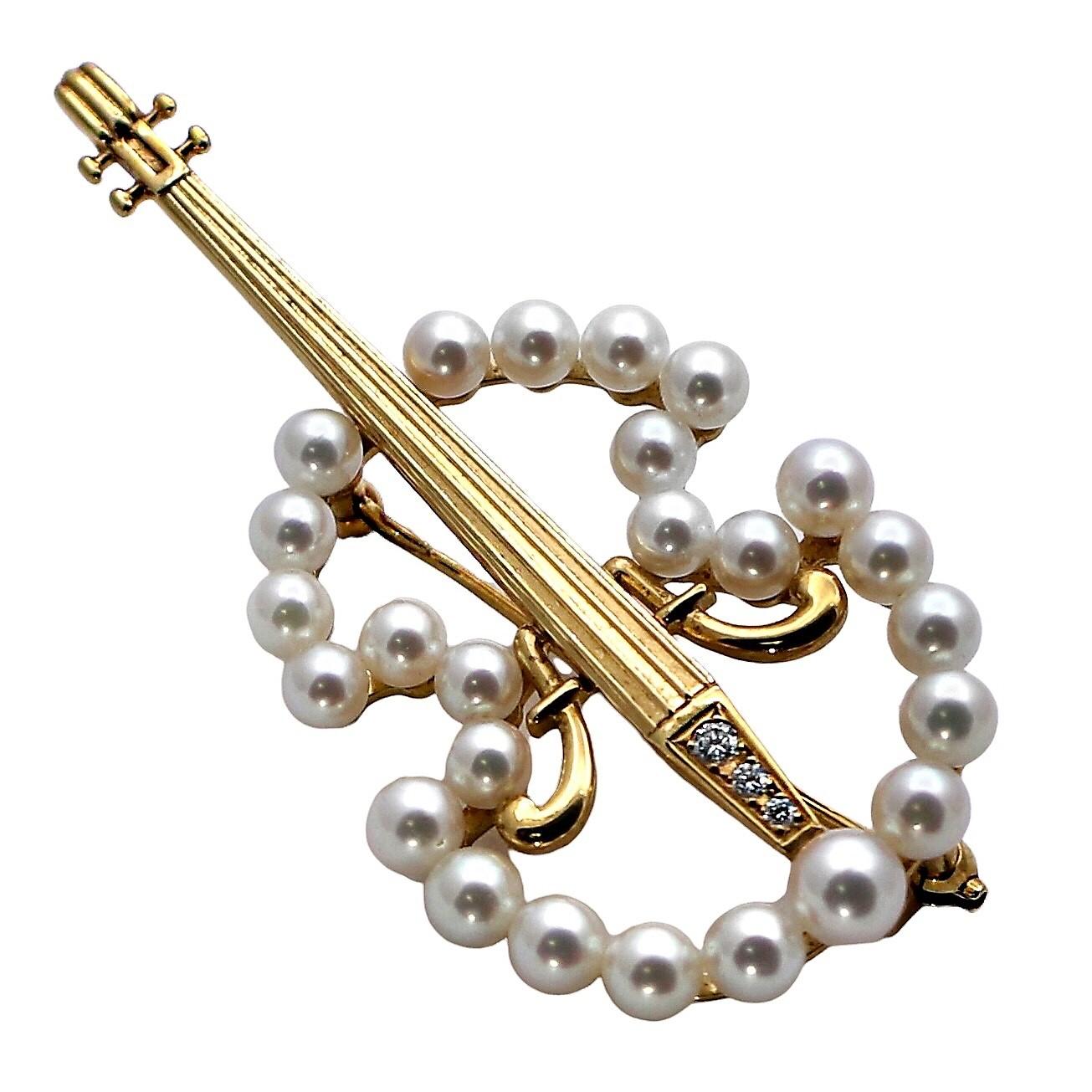 This very well crafted and artistic, vintage, 18K yellow gold violin brooch is set with 25 fine, Mikimoto Japanese cultured pearls measuring from 4.15mm to 4.35mm, as well as three brilliant cut diamonds. Total approximate diamond weight is .10ct
