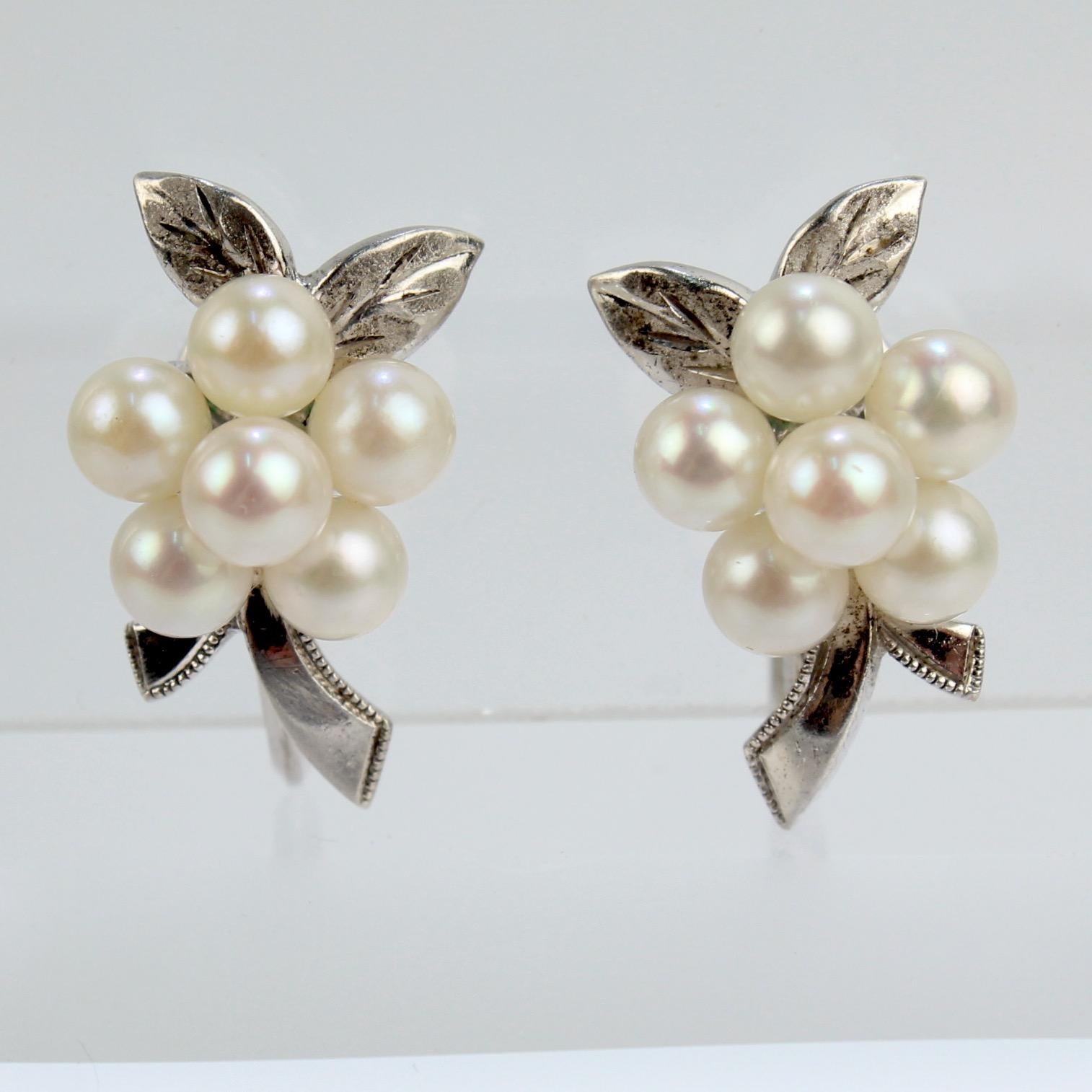 A very fine pair of vintage Mikimoto Akoya cultured pearl and sterling silver earrings.

Each with a pearl cluster set like a bouquet on two sterling silver leaves and stems.  

Secured with screw back closures. 

Wonderful Mikimoto