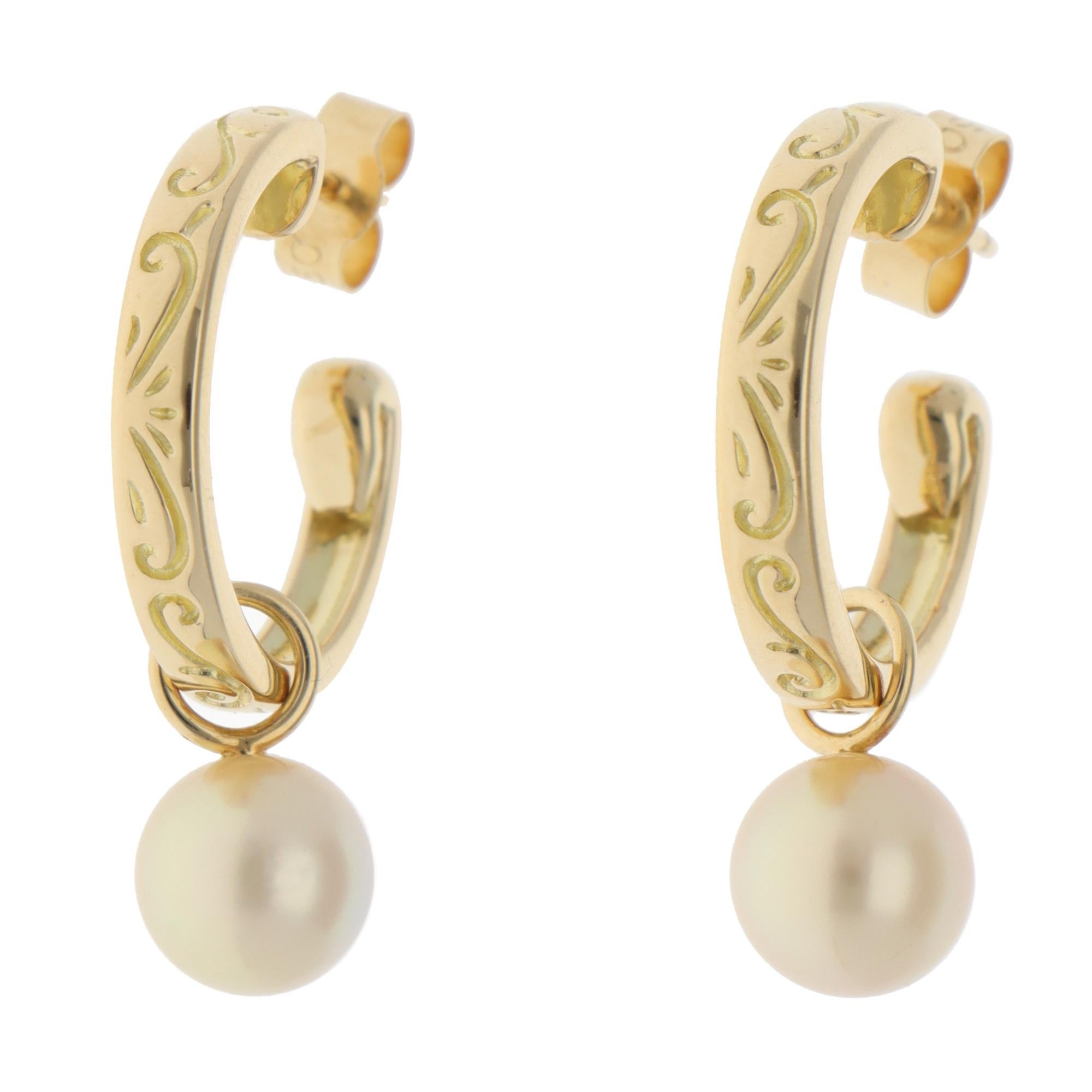 Un elegante par de pendientes de aro de perlas Mikimoto vintage engastados en oro amarillo de 18 quilates.

Cada pendiente está compuesto por un aro de 3 milímetros con bonitos detalles grabados. Una perla blanca dorada cuelga elegantemente de cada