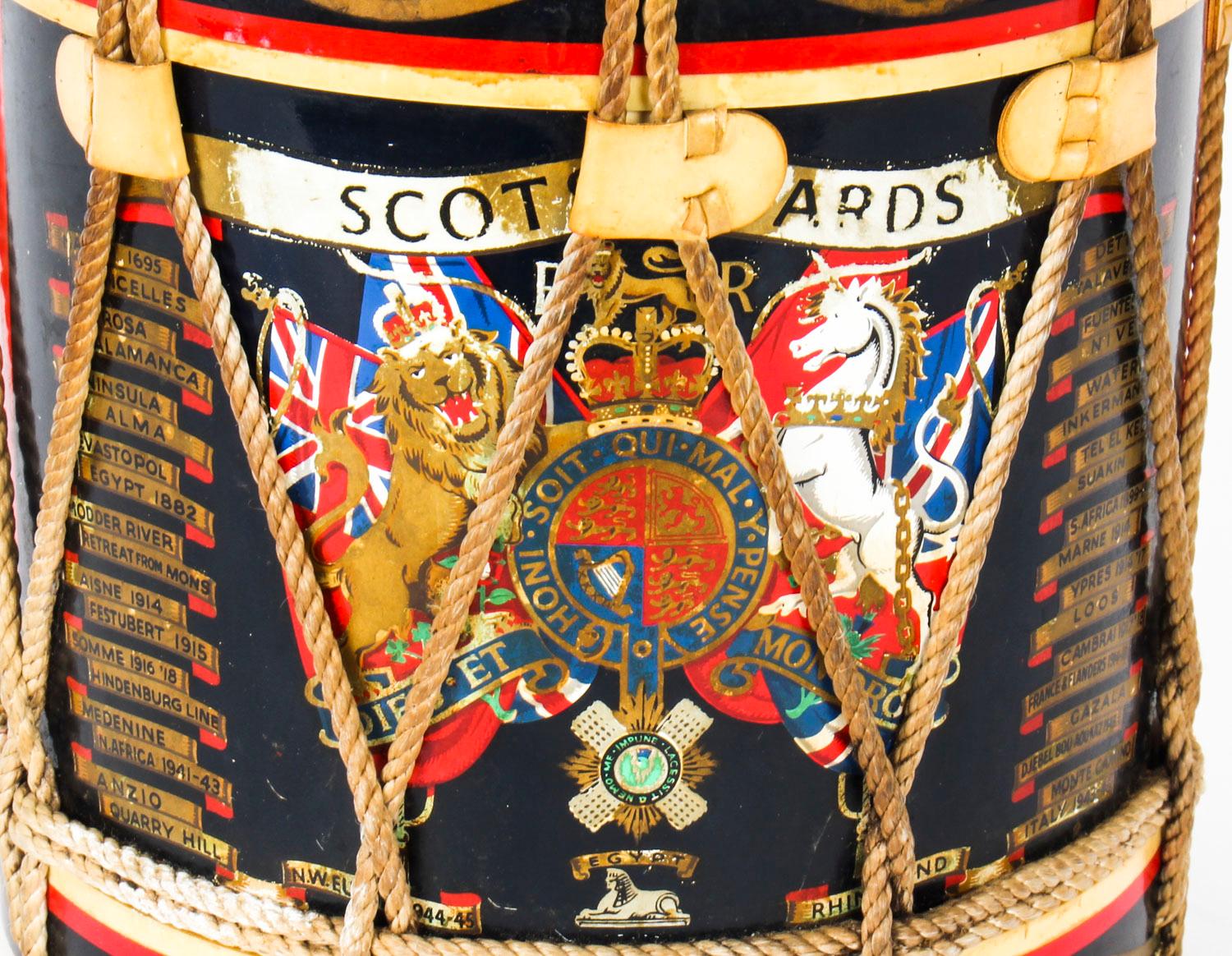 This is an elegant vintage ice bucket with lid, in the form of a military drum, dating from the mid-20th century.

The drum features a black and gold cylindrical body with a large Scots Guards regimental crest to the side and is embellished with