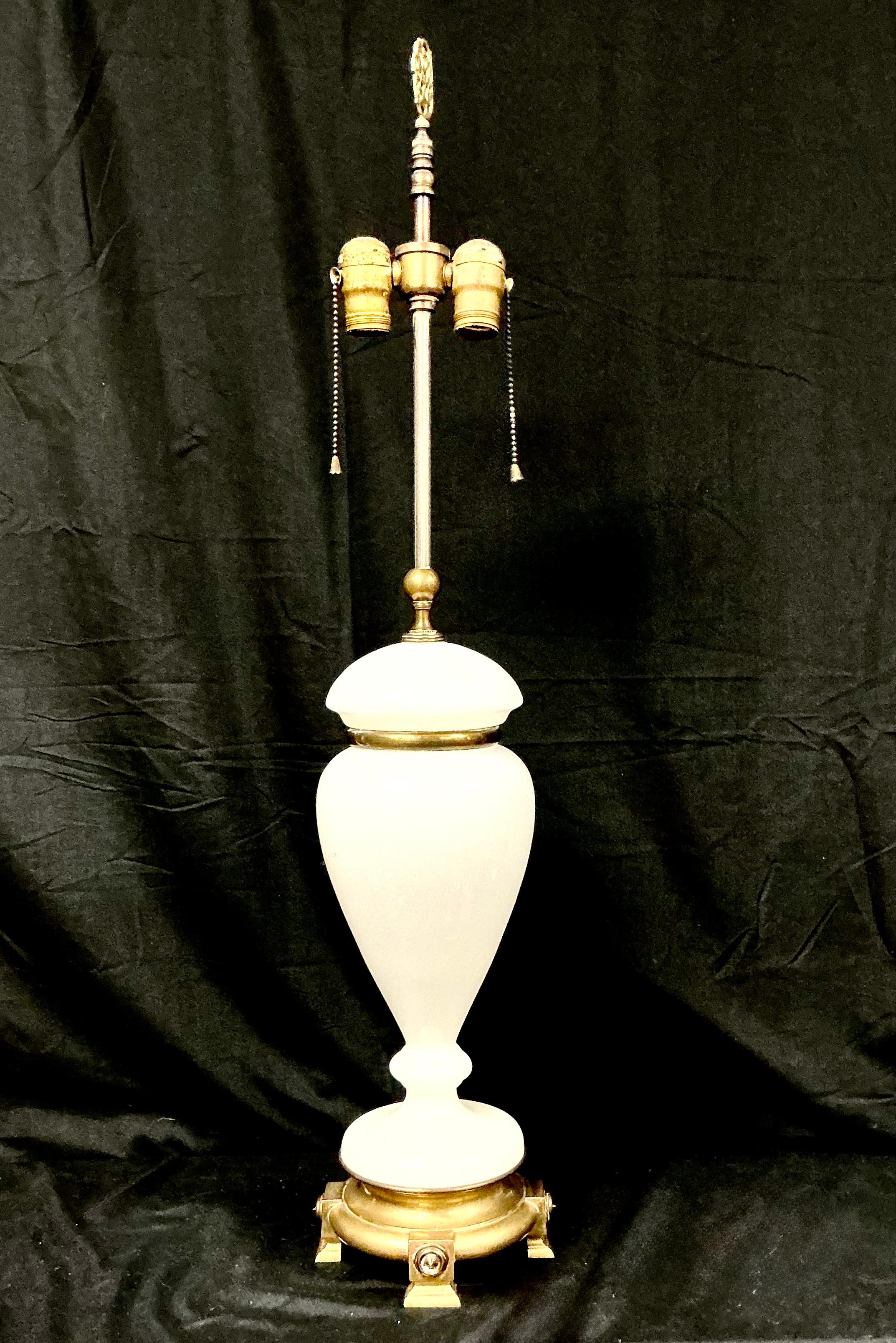 Lampe de table en verre au lait du 20e siècle, fabriquée en Amérique. La lampe Eleg se caractérise par un corps classique en forme d'urne  Fabriqué en verre de lait blanc opaque et lisse, complété par des accents métalliques dorés. La lampe repose