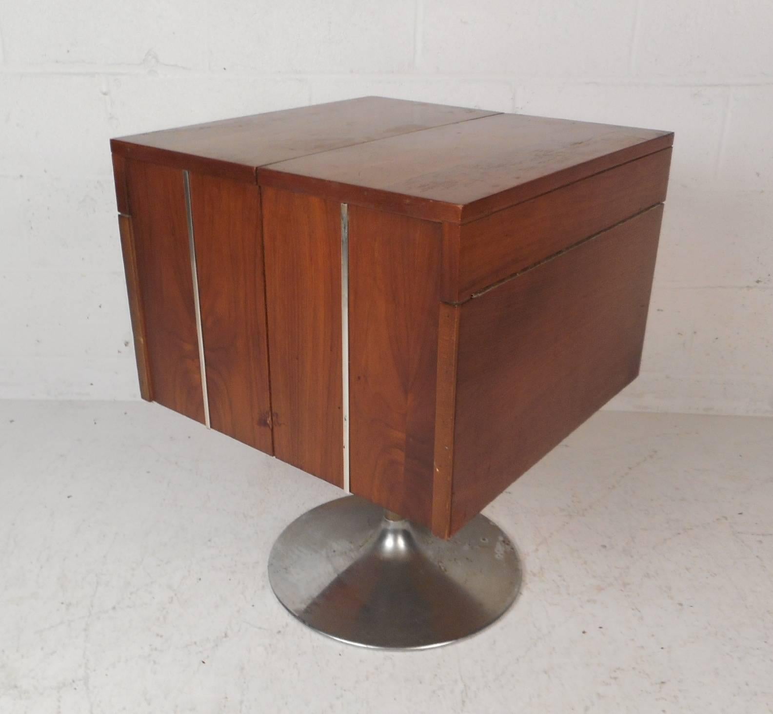 An amazing midcentury small mini bar by Lane! This compact bar opens up to unveil a 15 inch deep bar stash area with a drop in shelf. The top turns into a small table with a black laminate top meant to place cups on each side. Chrome strips on two