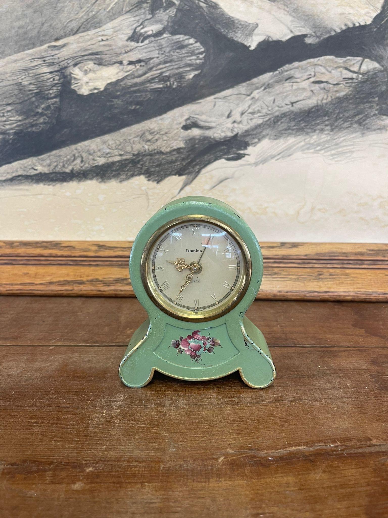This Clock plays Brahms Lullaby at the turn of the knob in the back. Original use was as an alarm Clock. Decorative Use, alarm and clock are not functional. Sage green colored with gold toned accents. Floral Motif on the front. Vintage Condition