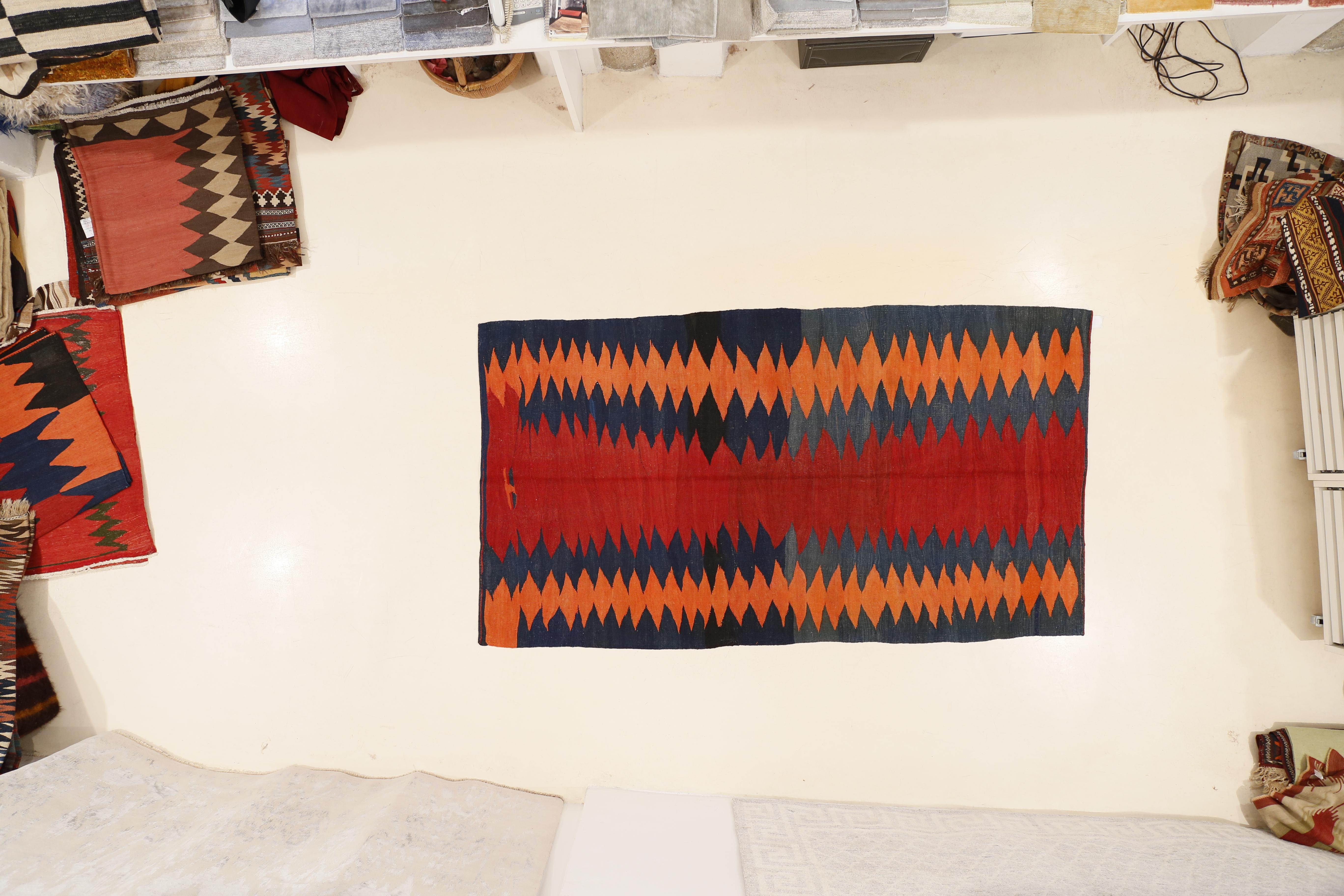 A powerful tribal Kilim distinguished by a central red open field flanked by blue and orange 'lightning' motifs. What characterizes this flat-weave is the sturdy texture, comparable in handle to a pile knotted rug.