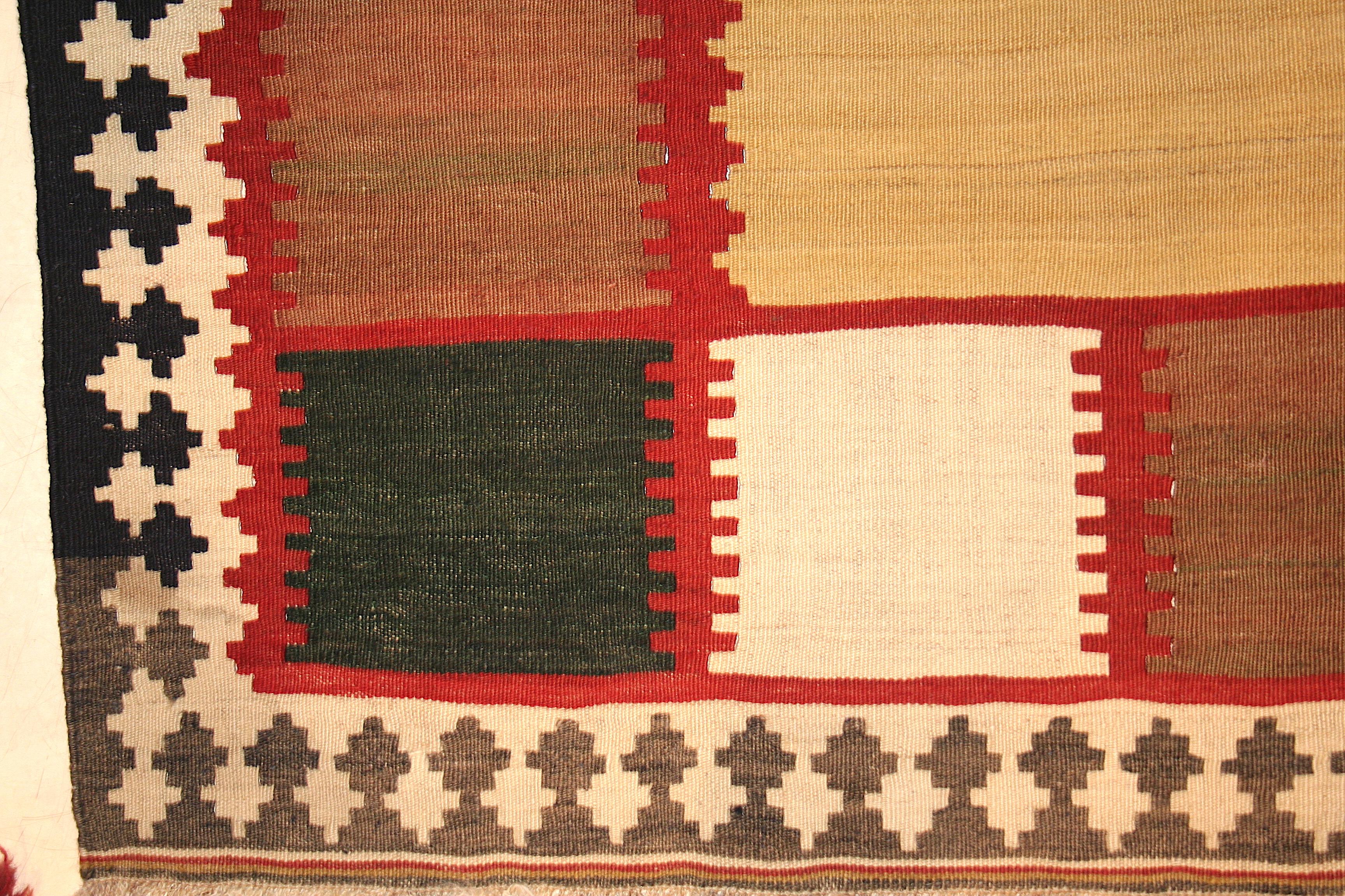 A stunning tribal kilim distinguished by a neutral open field and embellished by a checkerboard polychrome border. A great example of how tribal art sometimes embraces modernism, anticipating it by half a century.