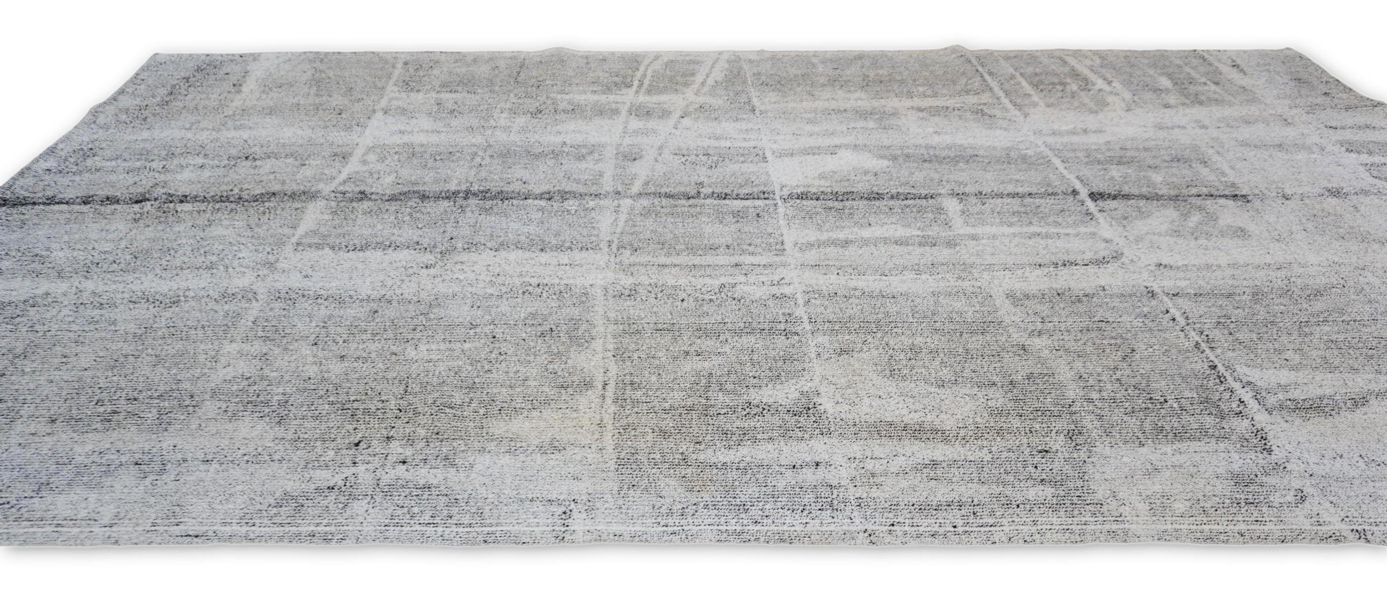 This wool flatweave rug is a stunning representation of contemporary minimalism, seamlessly blending modern aesthetics with traditional craftsmanship. The rug features an abstract grid-like pattern in a sophisticated palette of gray, greige, and