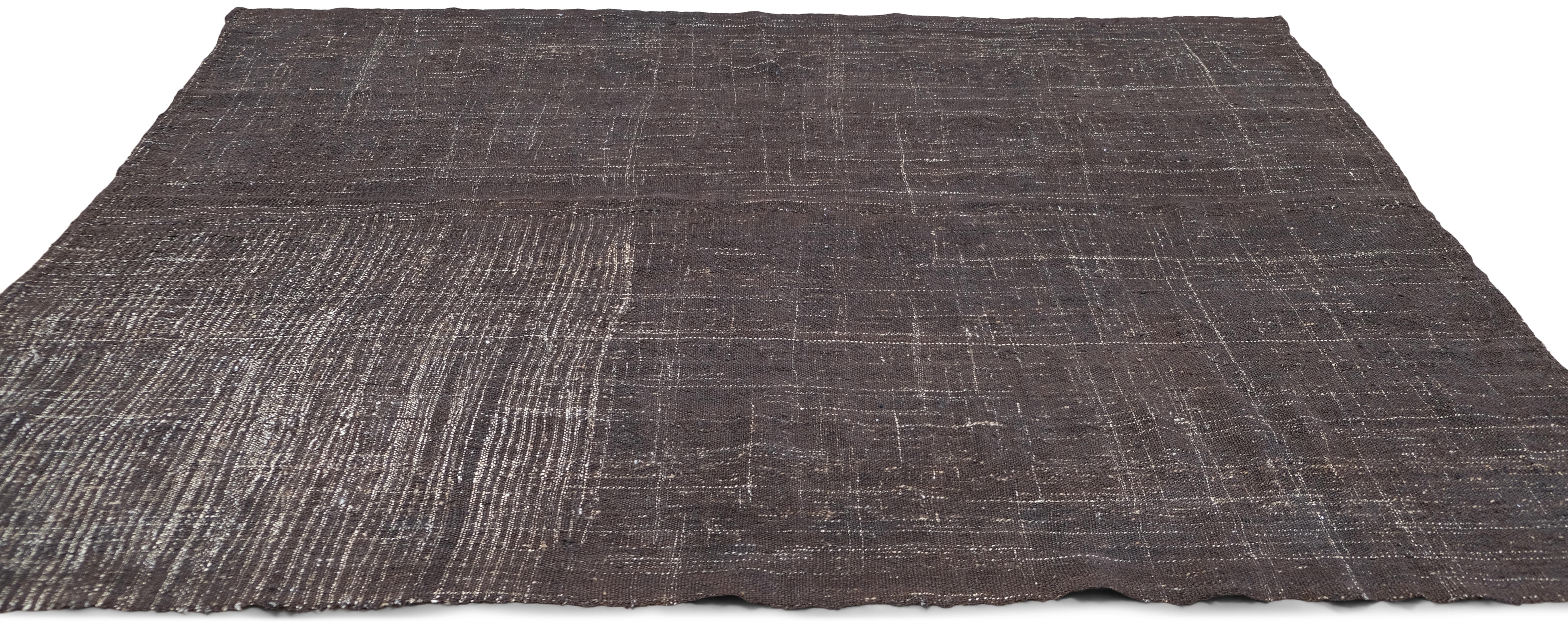 Immerse your space in timeless elegance with this handwoven wool/goat hair rug. Showcasing an intricate blend of earthy tones and abstract linear patterns, this vintage rug exudes a rustic yet refined aesthetic. The subtle texture created by the