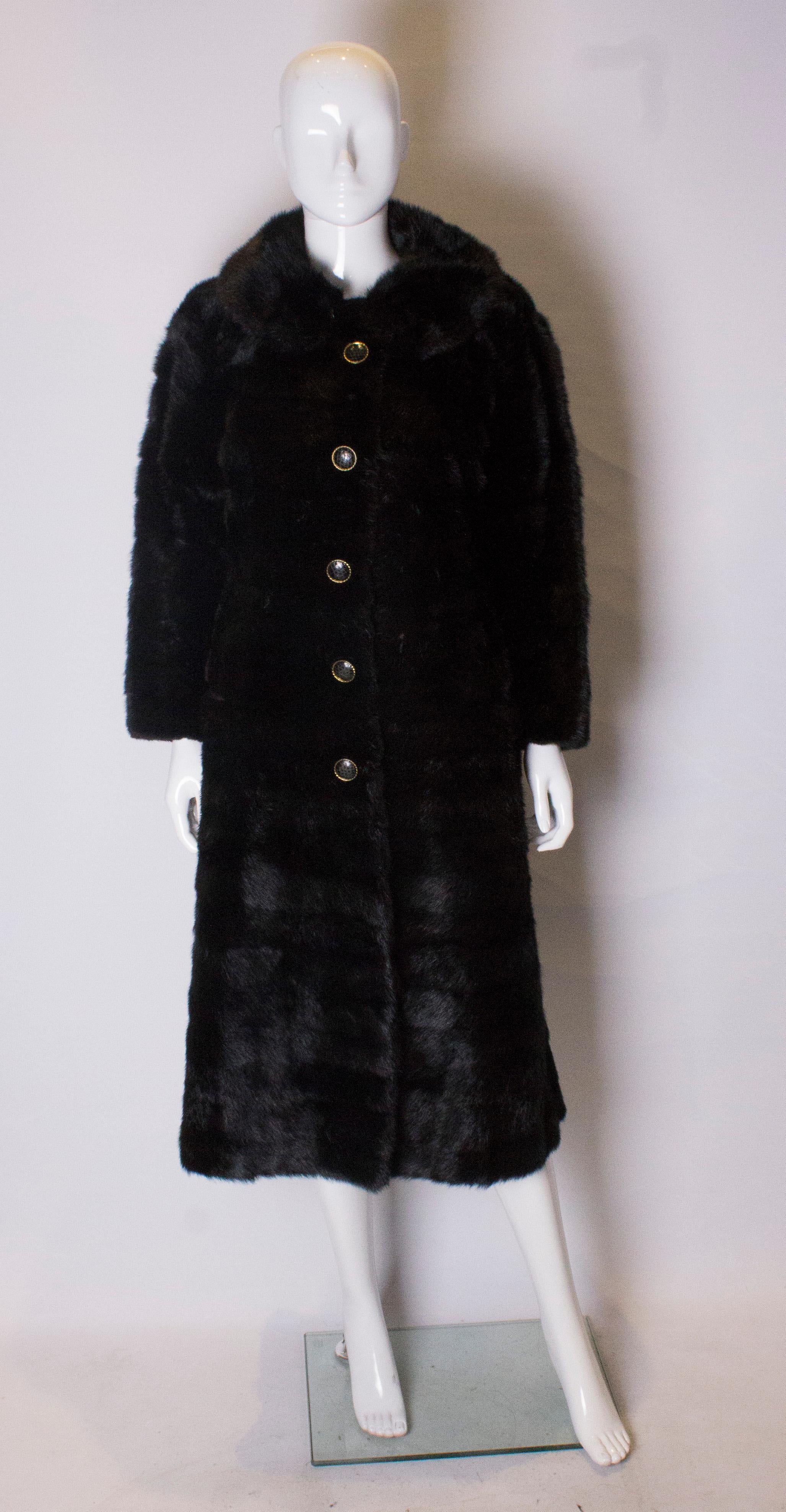 A chic vintage mink coat dating from the late 1960s. The coat has a four hook opening with four decorative buttons. It has a round collar with hook fastening and one pocket on either side at the front, and a half belt at the back. The coat is fully