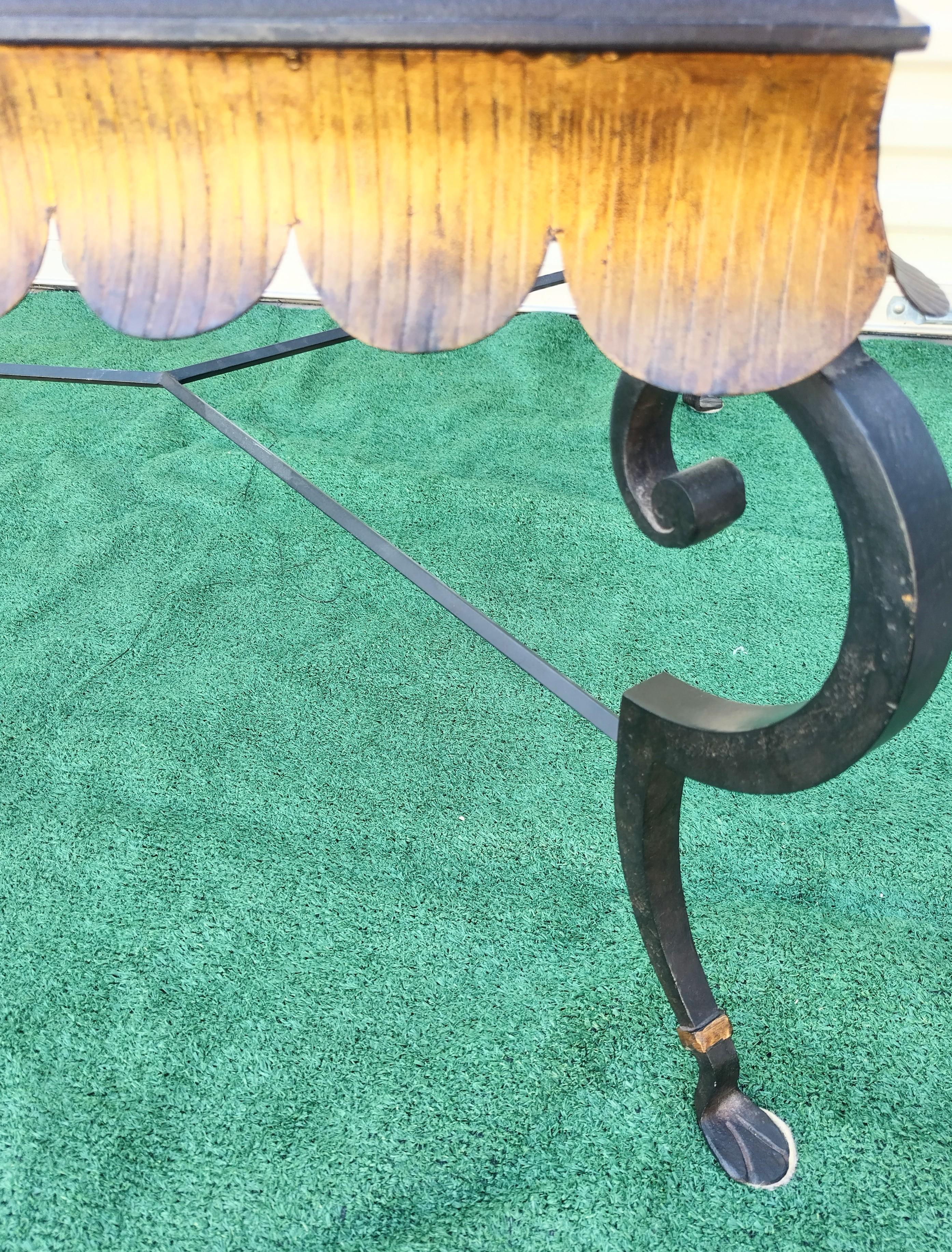 Vintage large elegant coffee table by Minton Spidell.
The table features a black iron base with gold gilt metal scalloped edge and curved legs.
The scalloped detail is made of hard metal and has been finished in an antique gold patina which enhances