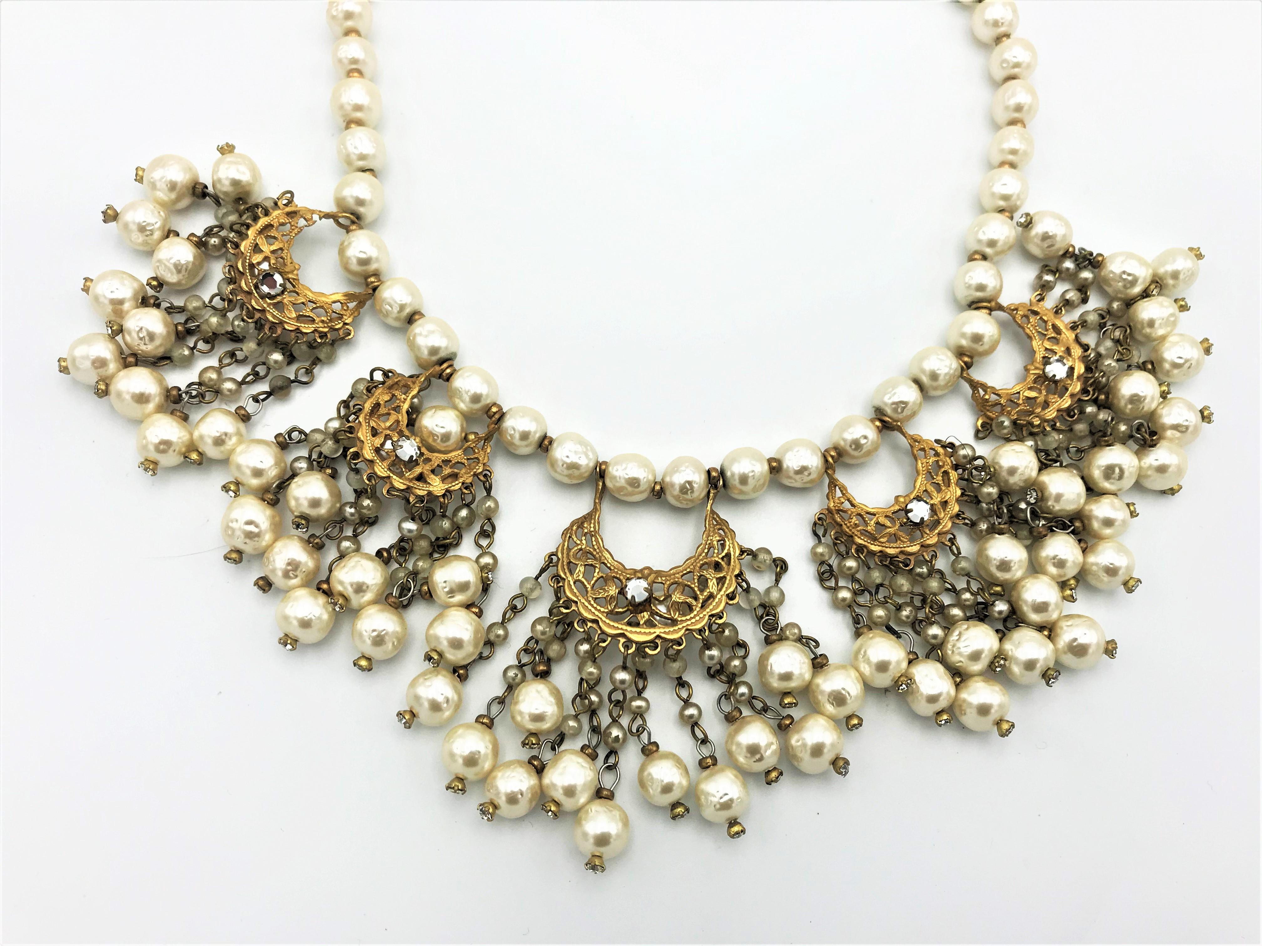 A very rare and beautiful wearable necklace with matching ear clip by Miriam Haskell. The necklace 42 cm long, made of fake barock pearls.
5 Indian crescent moons with 13 pearl tassels each hang on it. The claps is made of the floral motif covered