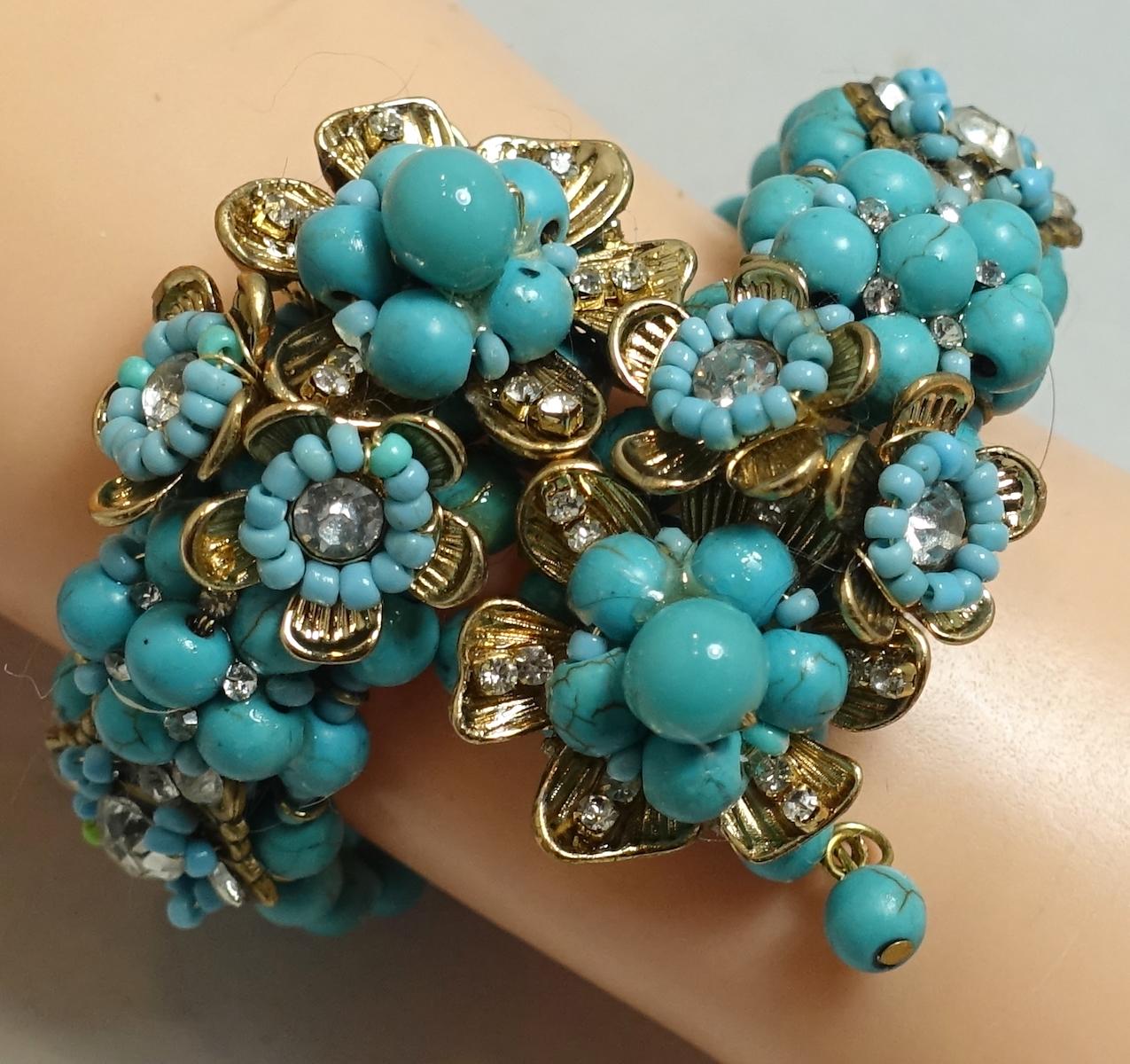 We believe this is a Miriam Haskell vintage wrap bracelet with burgundy glass beads in the center with clear crystals in a floral design. This wrap bracelet is in a gold tone setting and measure 9” around the inside. The centerpiece is 1” wide and