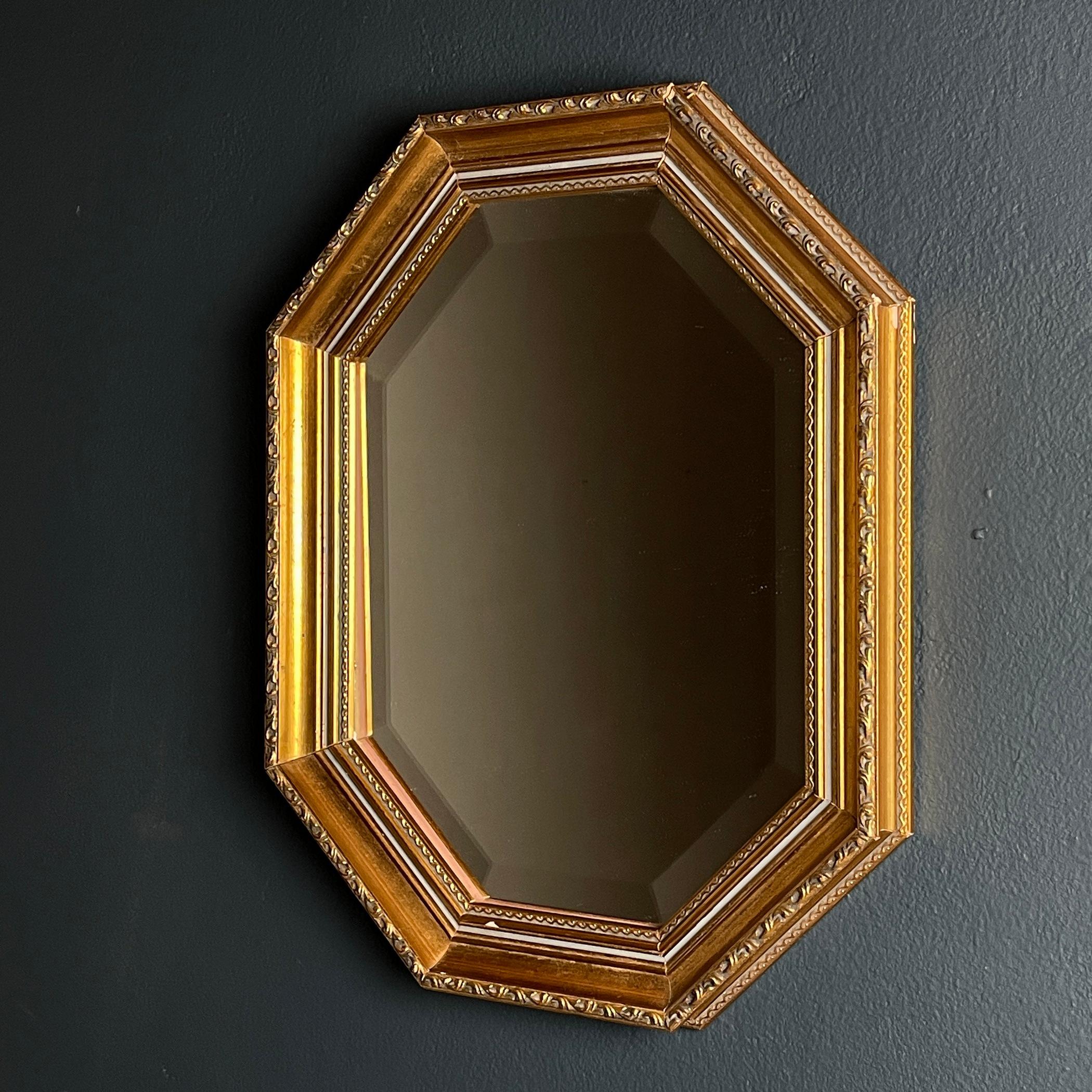 Behold a vintage mirror encased in an octagonal wooden frame adorned with a lustrous gold finish. This wall-mounted piece, a product of Italian craftsmanship dating back to the 1940s-1950s, exudes a timeless allure. The gilded wooden frame not only