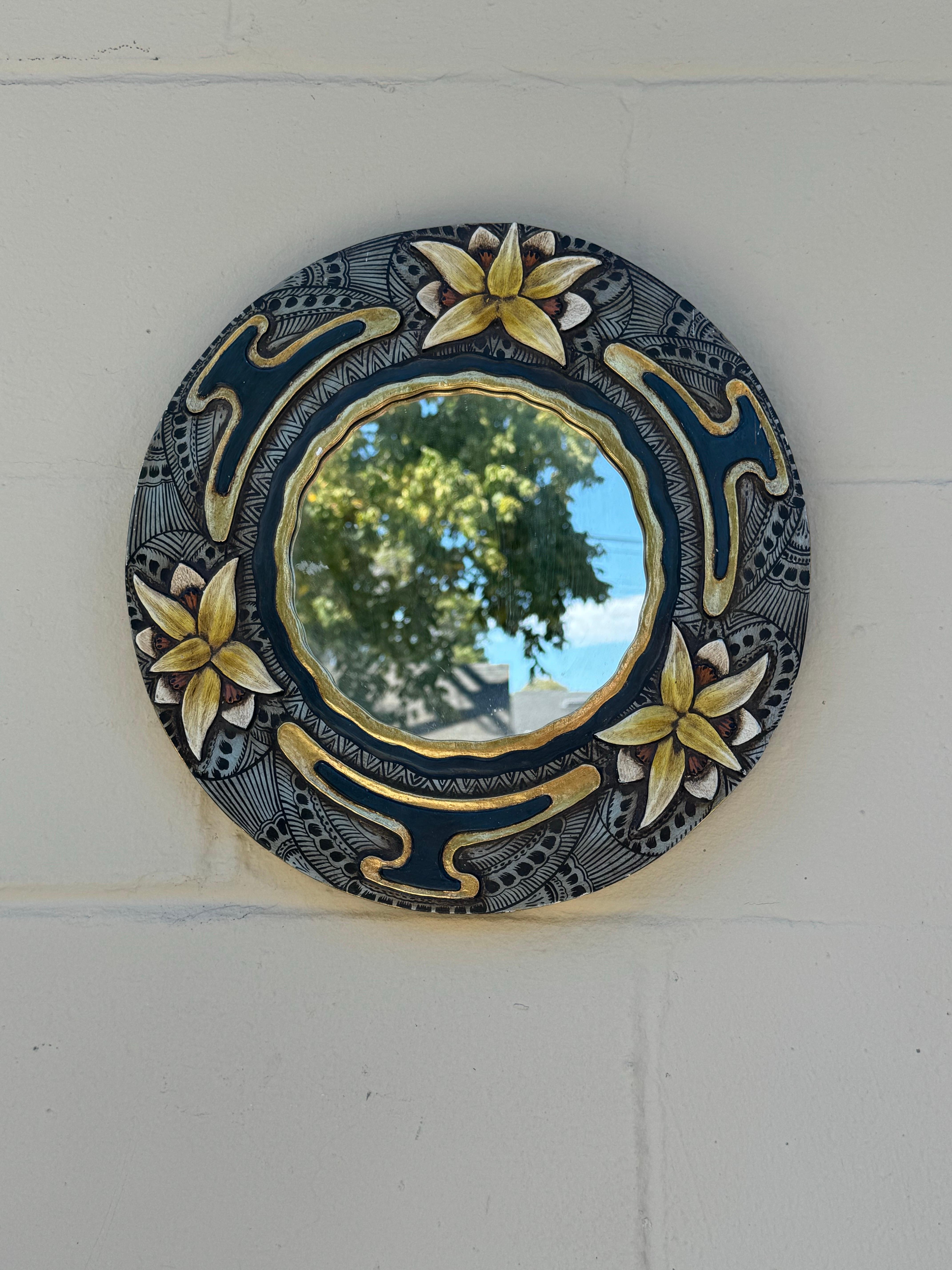 Élevez votre espace avec ce superbe miroir vintage.

Cette pièce captivante présente un cadre en bois sculpté à la main de manière complexe, orné de motifs floraux vibrants dans des tons bleus, jaunes, blancs et dorés. Le miroir lui-même est en