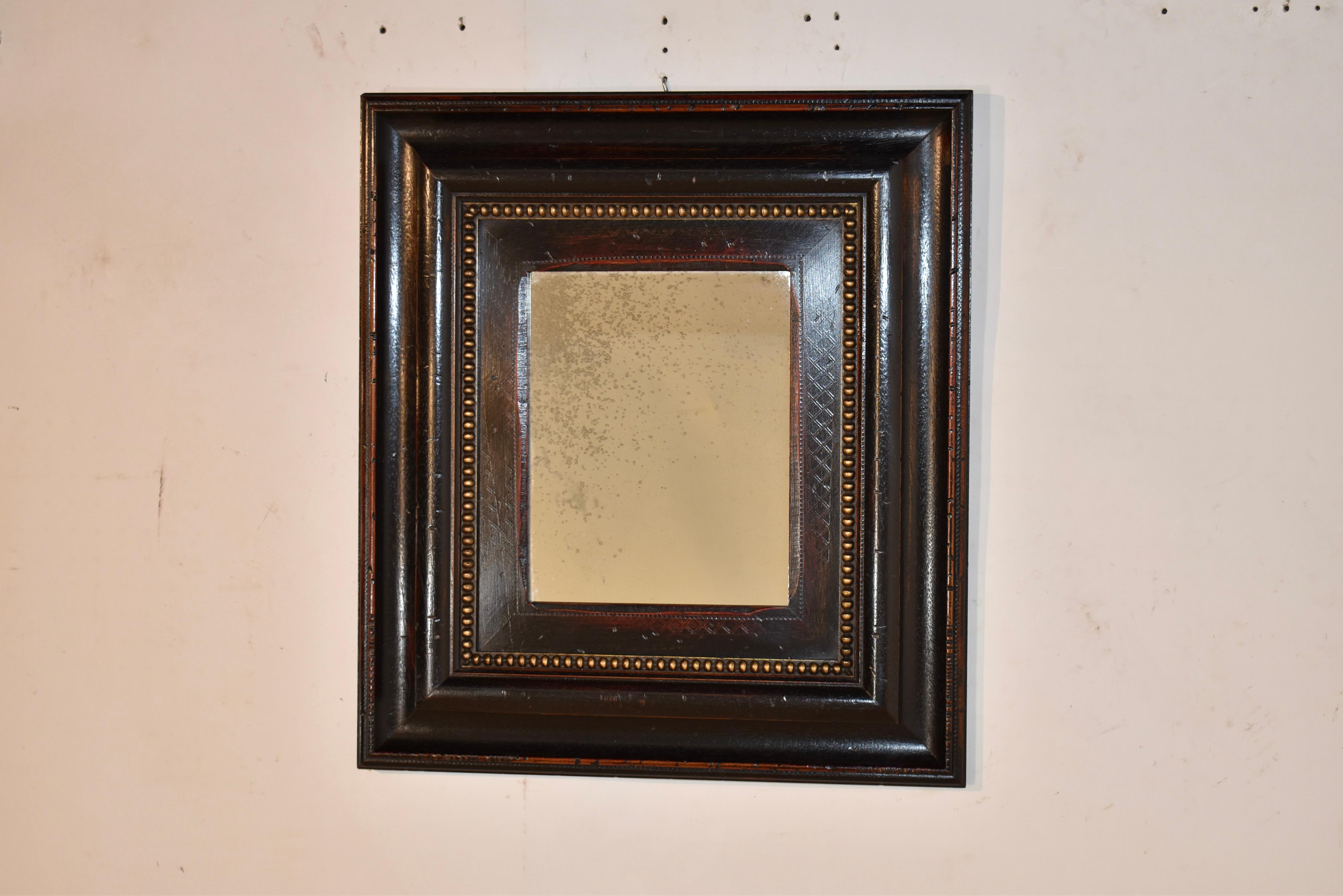Vintage wall mirror with a wide, handmade frame in  rubbed black finish with highlights in gold beading.  The frame surrounds a mercury glass mirror.  The quality of this frame is wonderful and will add design interest to any room in a house or