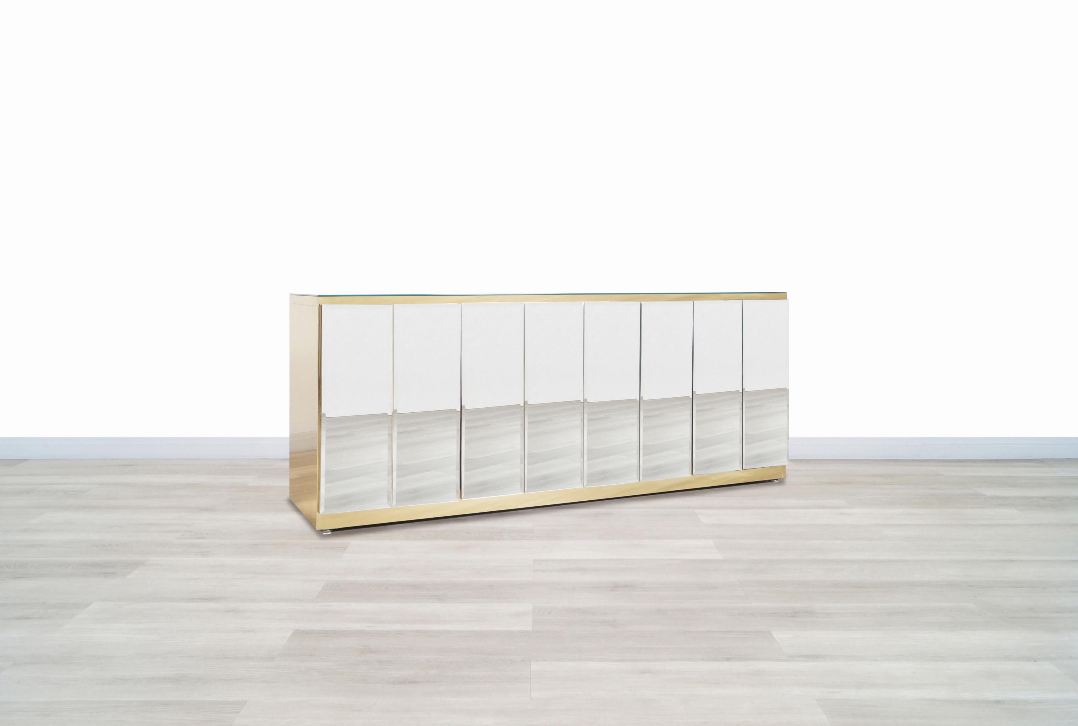 Beautiful vintage mirrored and brass credenza designed by Ello Furniture in United States, circa 1970s. This credenza or sideboard features four doors that are made up of elegant mirrors with beveled edges that offer a different touch to the view.