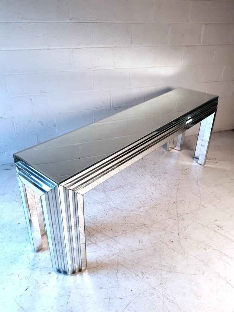 Stylish vintage console table with mirrored panels lining the entirety of the piece. The tabletop's panel has beveled edges. Interesting design with accents on the sides and corners. Please confirm the item's location with the dealer (NJ or NY).