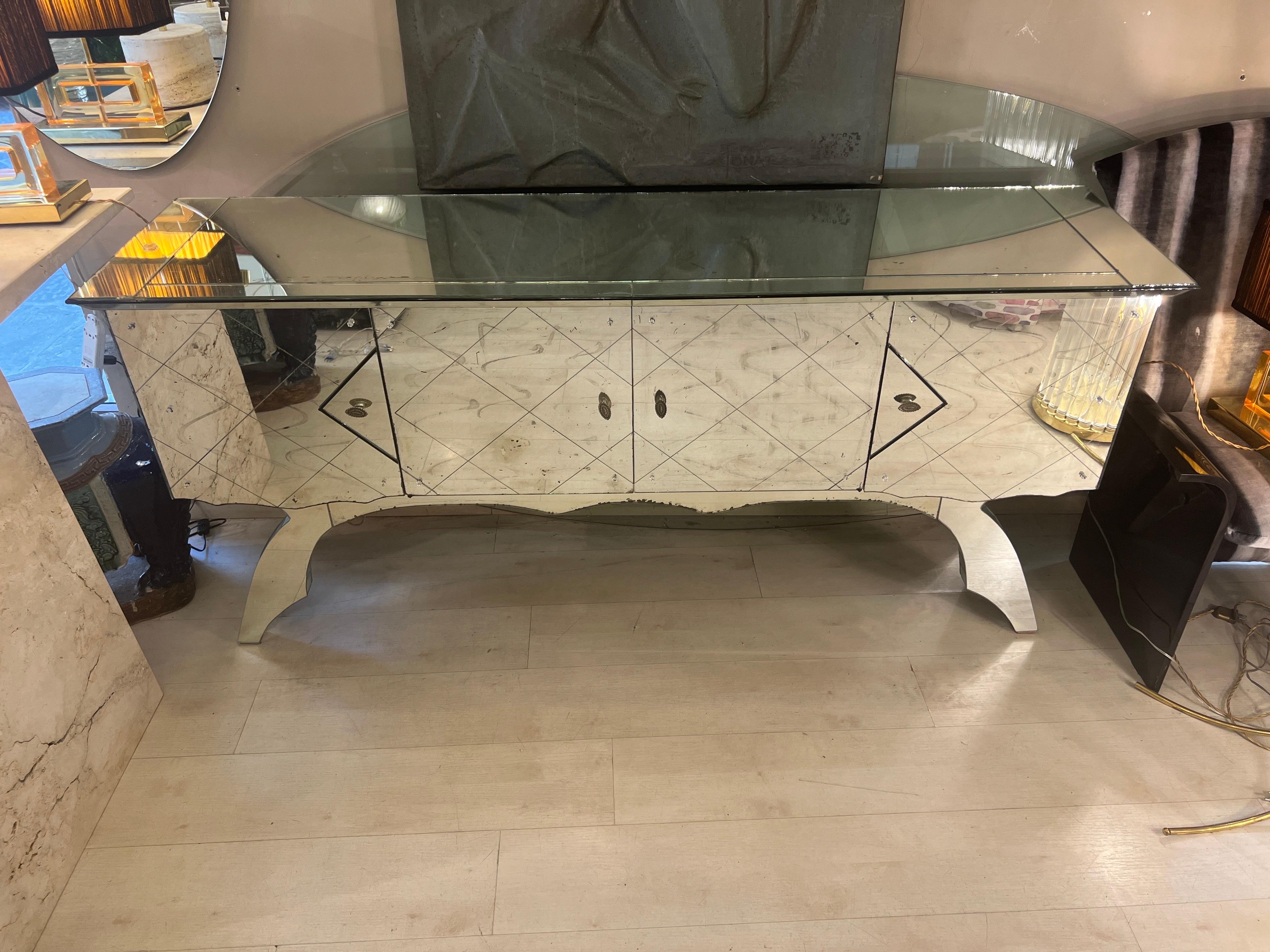 Vintage Mirrored Credenza with 4 doors, moustache legs with mosaic mirrors.
The front doors have a geometric design glass engravings and silvered handles. The structure of the credenza and the inside is made of maple wood.
Please note that the