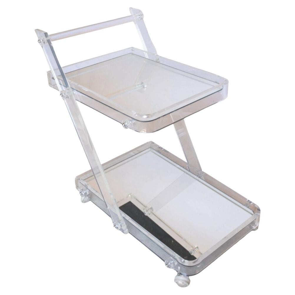 A glamorous nod to 1970s modernism, this vintage bar cart features a sleek Lucite frame with clean lines and striking transparency. Two mirrored surfaces reflect light beautifully, adding depth and dimension, while original polished chrome casters