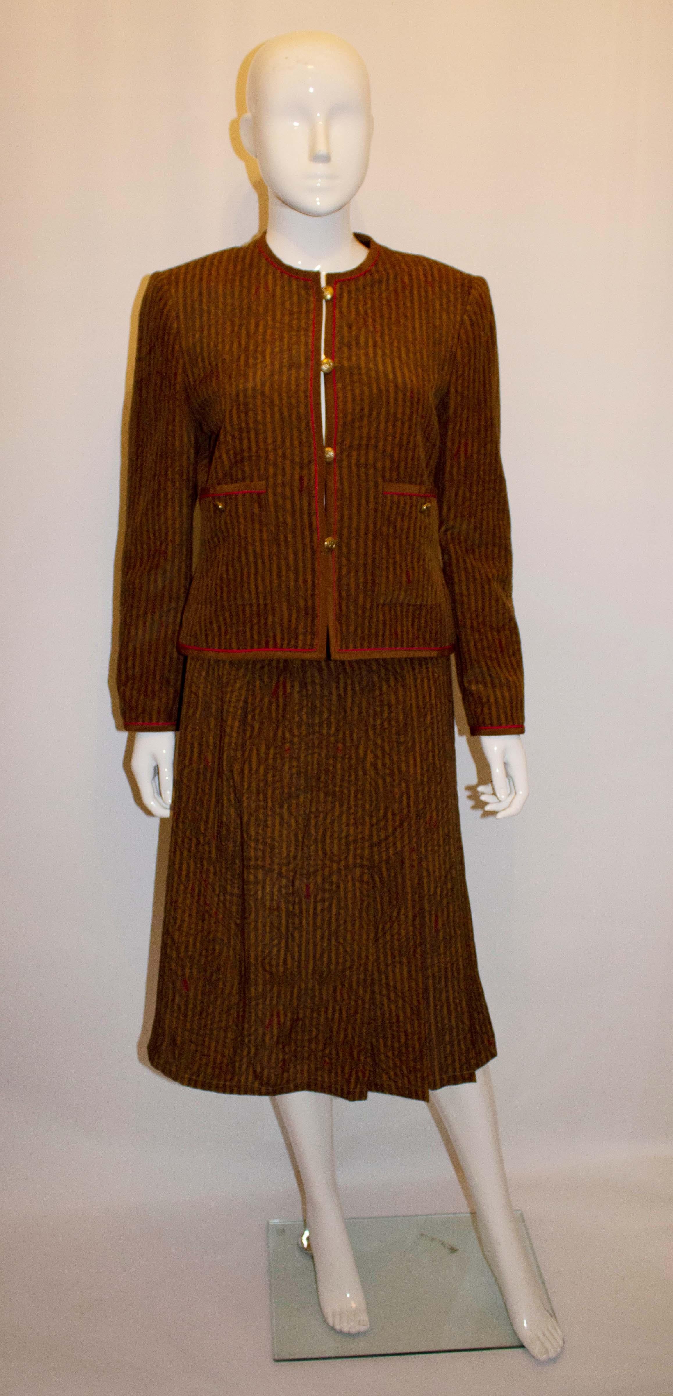 A chic vintage, chanel style , silk skirt suit by Miss Antonette .The collaraless jacket is in a soft brown colour with pink trim, and has two front pockets, and a three button cuff. The skirt is fully lined with sewn in pleats, and has a button