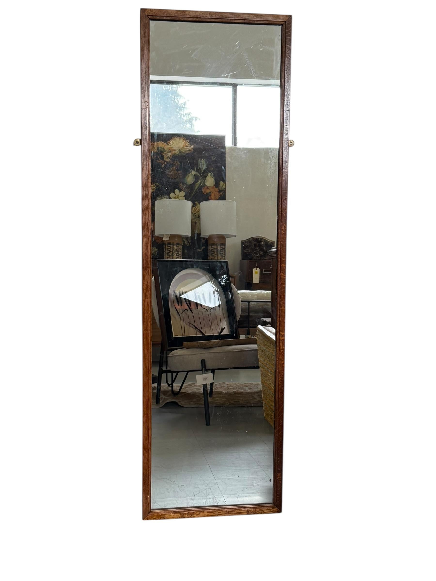 Ce miroir de sol vintage en chêne Mission est une pièce remarquable au design minimaliste mais élégant, caractéristique du mouvement Arts and Crafts. Sa haute structure rectangulaire est fabriquée en chêne massif, présentant un grain de bois riche