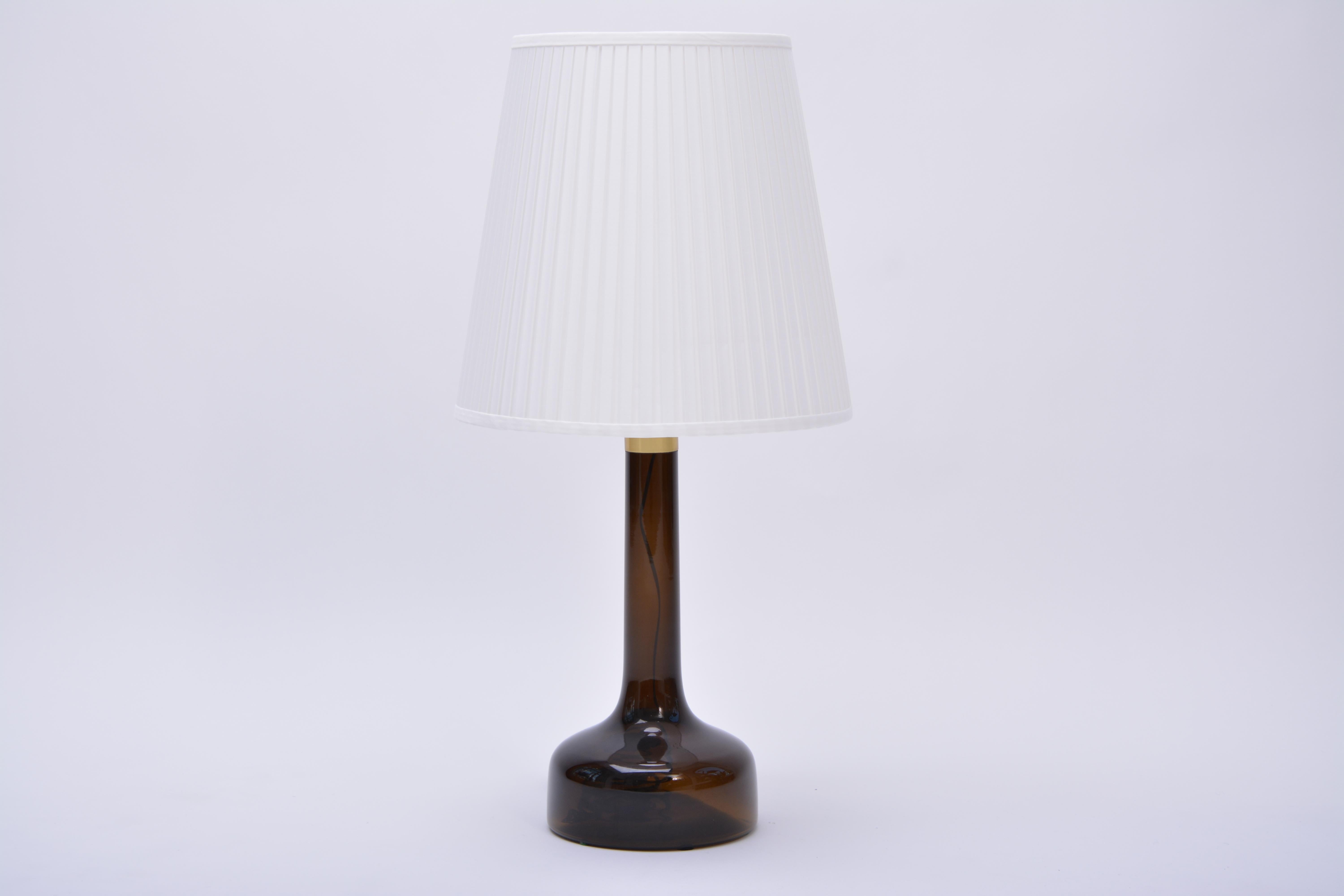 Danish Mid-Century Modern model 343 brown Glass table lamp from Le Klint, 1960s

Vintage midcentury glass lamp designed and produced by Le Klint in Denmark in the 1960s.
The lamp is made of brown glass and has a brass ring. New shade.