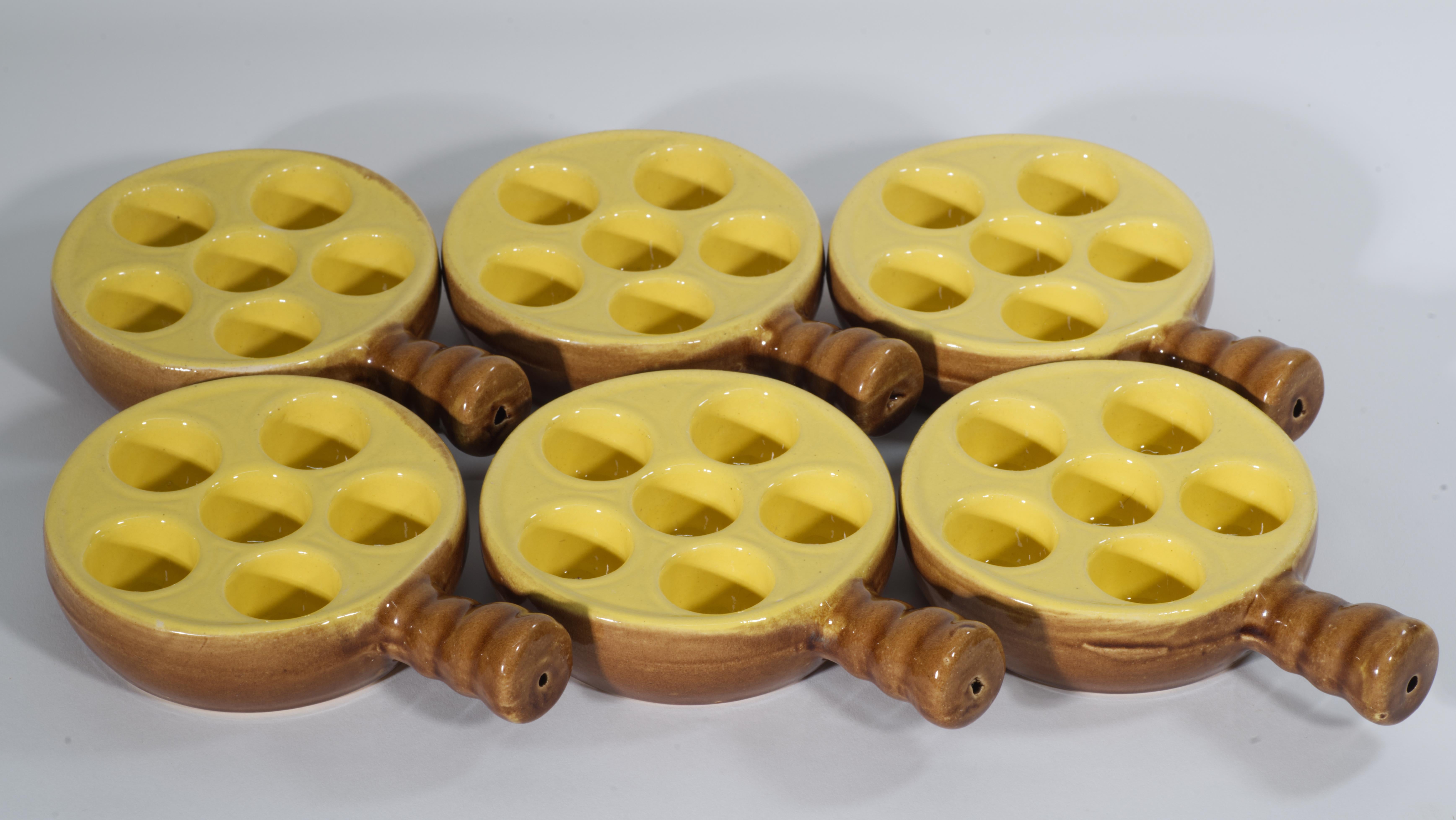 Les plats à escargots en céramique vintage présentent une forme de style moderne du milieu du siècle, avec une glaçure jaune beurre sur le dessus du plat et une glaçure marron clair sur les côtés, le fond et les poignées. Chaque poignée a un trou de