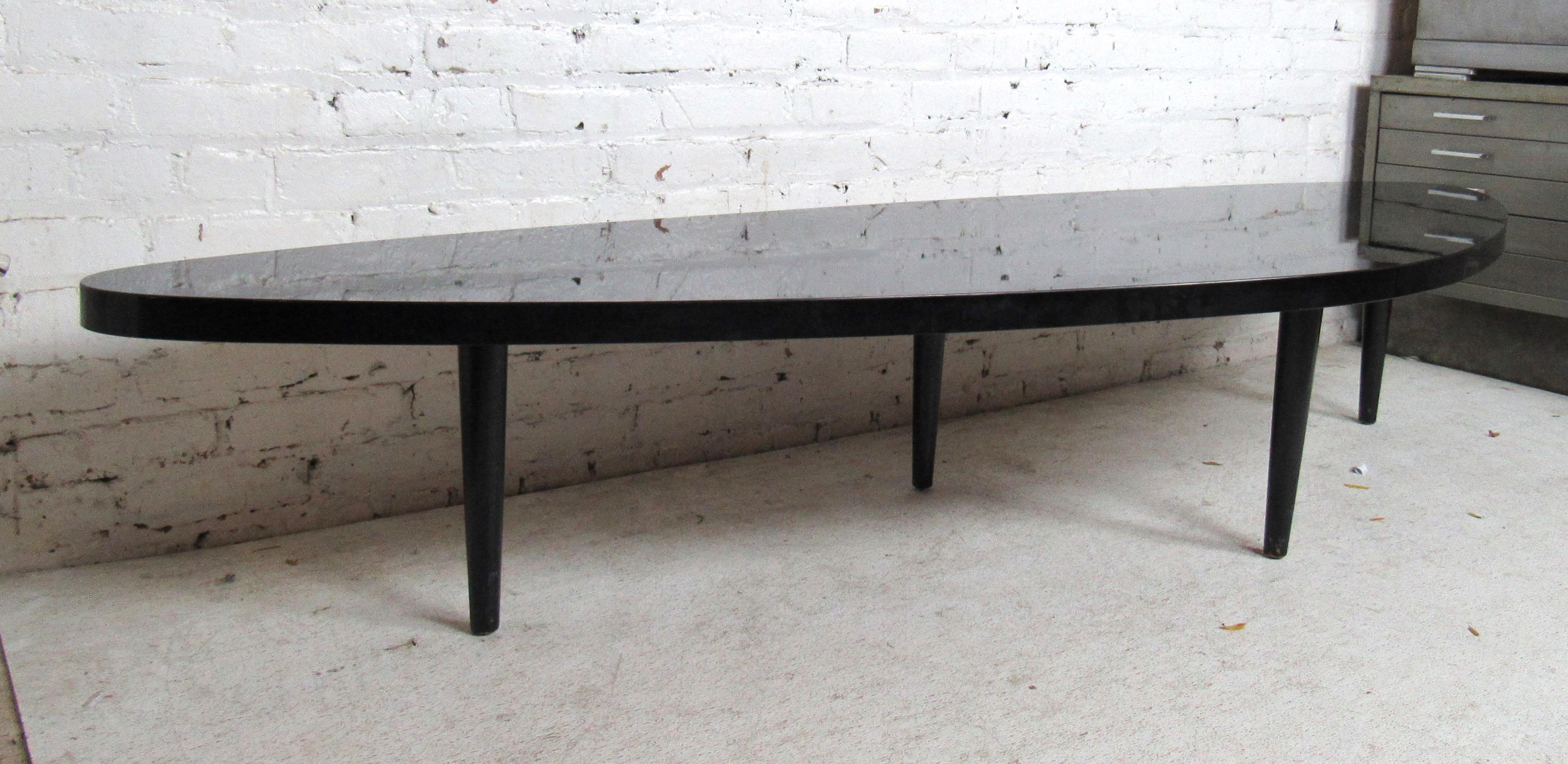 Unique Mid-Century Modern black laminate coffee table features four tapered legs and an odd shaped top.

Please confirm item location (NY or NJ).