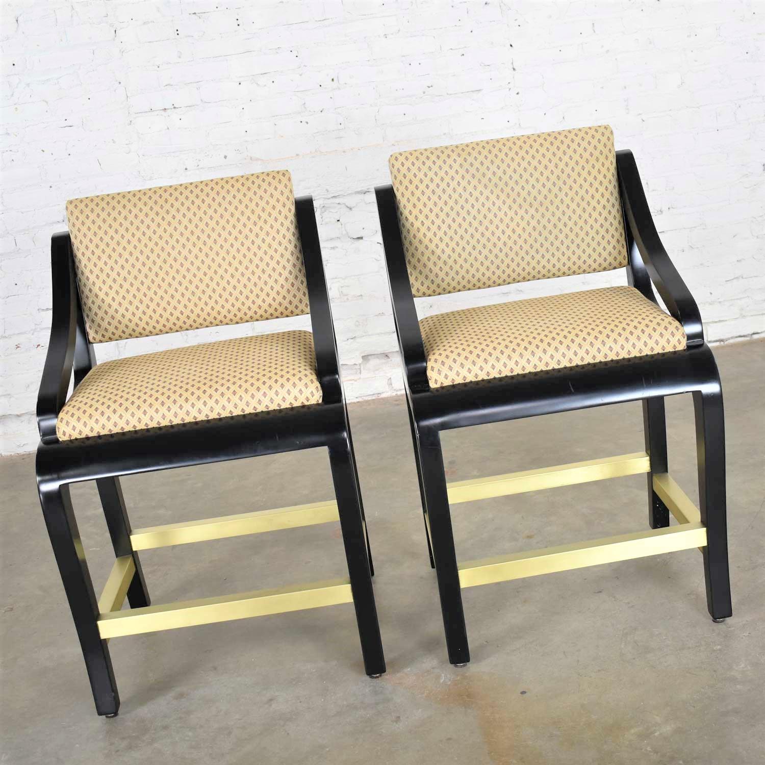 Handsome pair of modern counter height bar stools with a black painted frame, square brass foot rungs, and upholstered seat and back made by Stewart Furniture Manufacturing Co., Inc. for Beverly Interiors. They are in wonderful vintage condition.