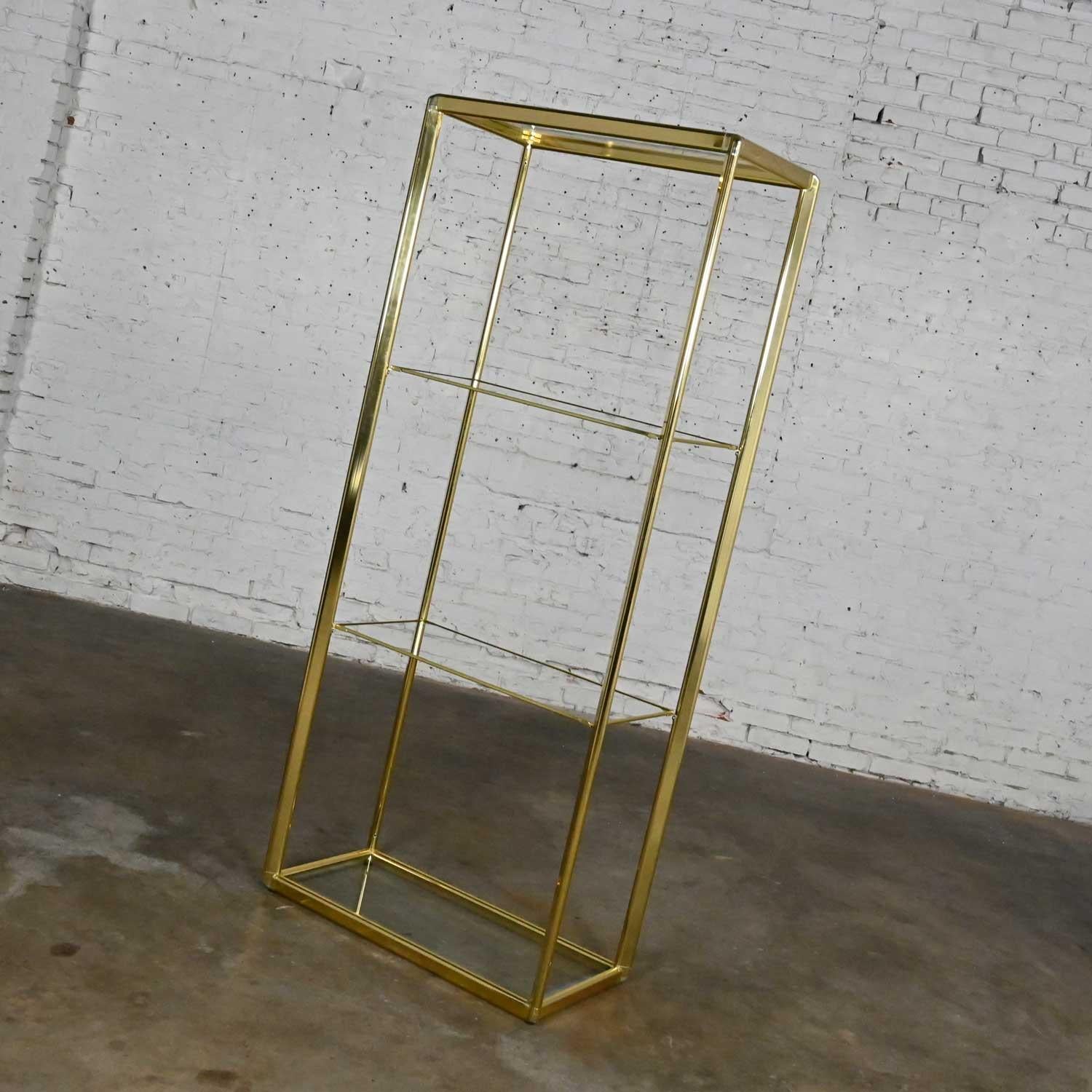 Stunning vintage Modern brass plate & glass etagere in the style of Design Institute of America or DIA. Comprised of a brass plated aluminum frame and four brass plated plastic trimmed glass shelves. Beautiful condition, keeping in mind that this is