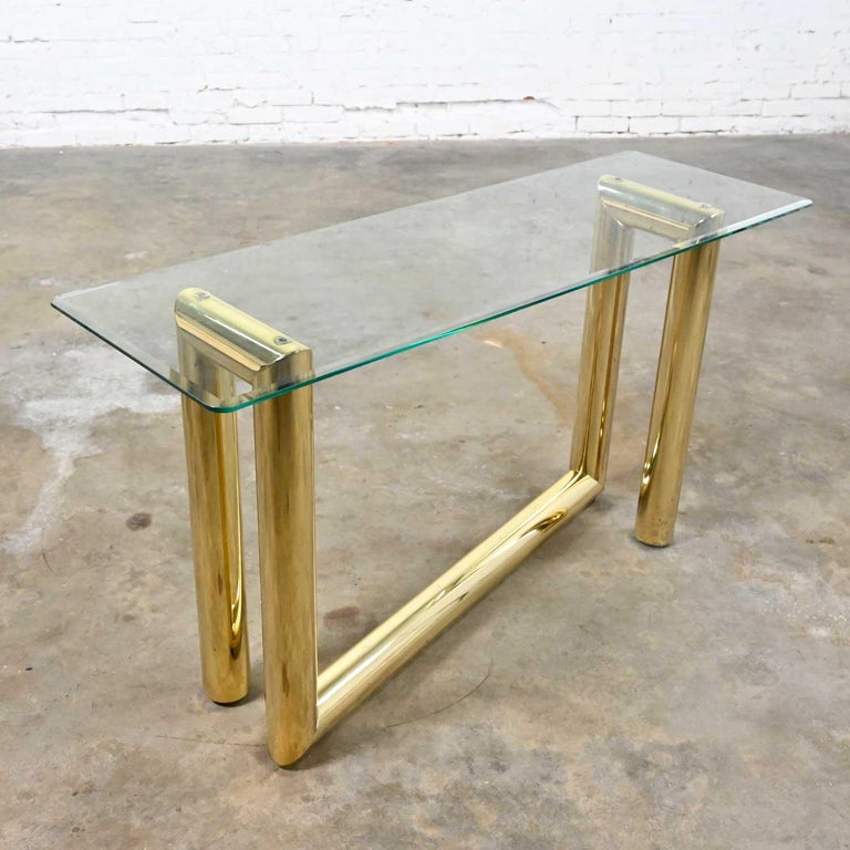 Gorgeous vintage modern brass plated console or sofa table with rectangular glass top in the style of Karl Springer. Beautiful condition, keeping in mind that this is vintage and not new so will have signs of use and wear. There are several areas of