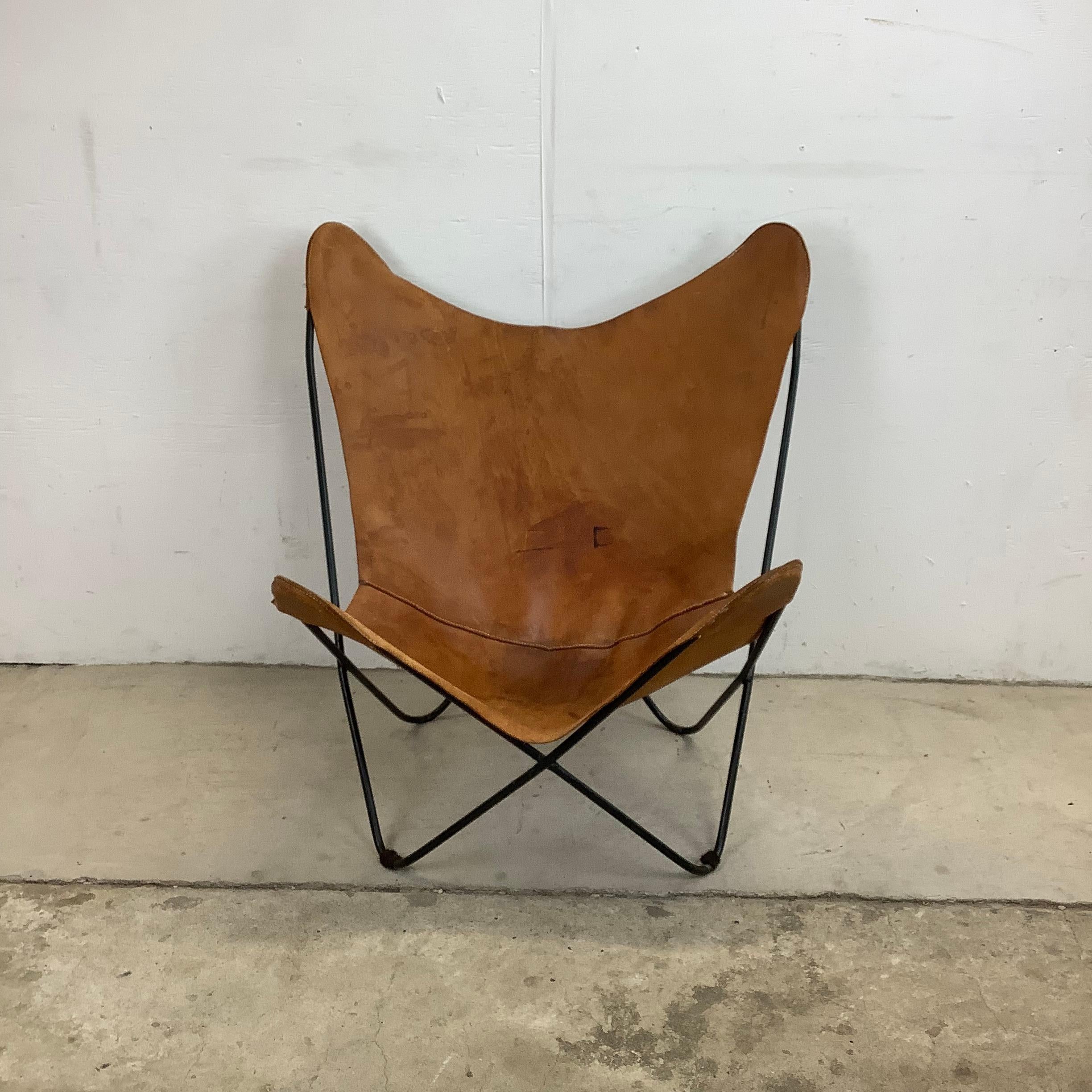 This mid-century period butterfly side chair features a sturdy iron BKF frame slung with patinated leather seat. The iconic comfort and minimalist modern design of this sought after side chair have ensured it to be a favorite for home or business