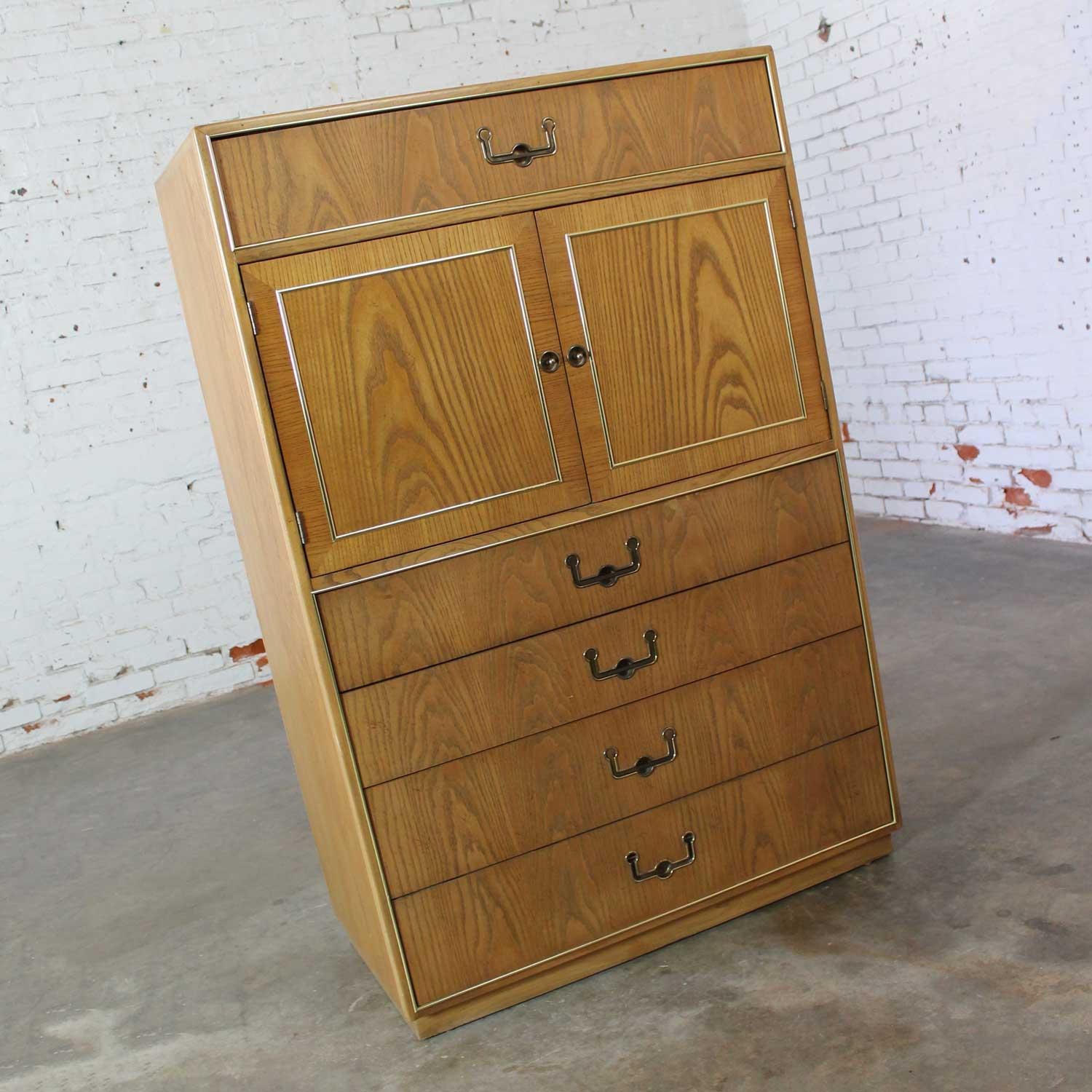 Handsome vintage modern Campaign style oak Gentleman’s chest by Founders Furniture. Comprised of book matched oak veneer, six drawers and two double doors with brass toned hardware, and brass plated beading detail. Beautiful condition, keeping in