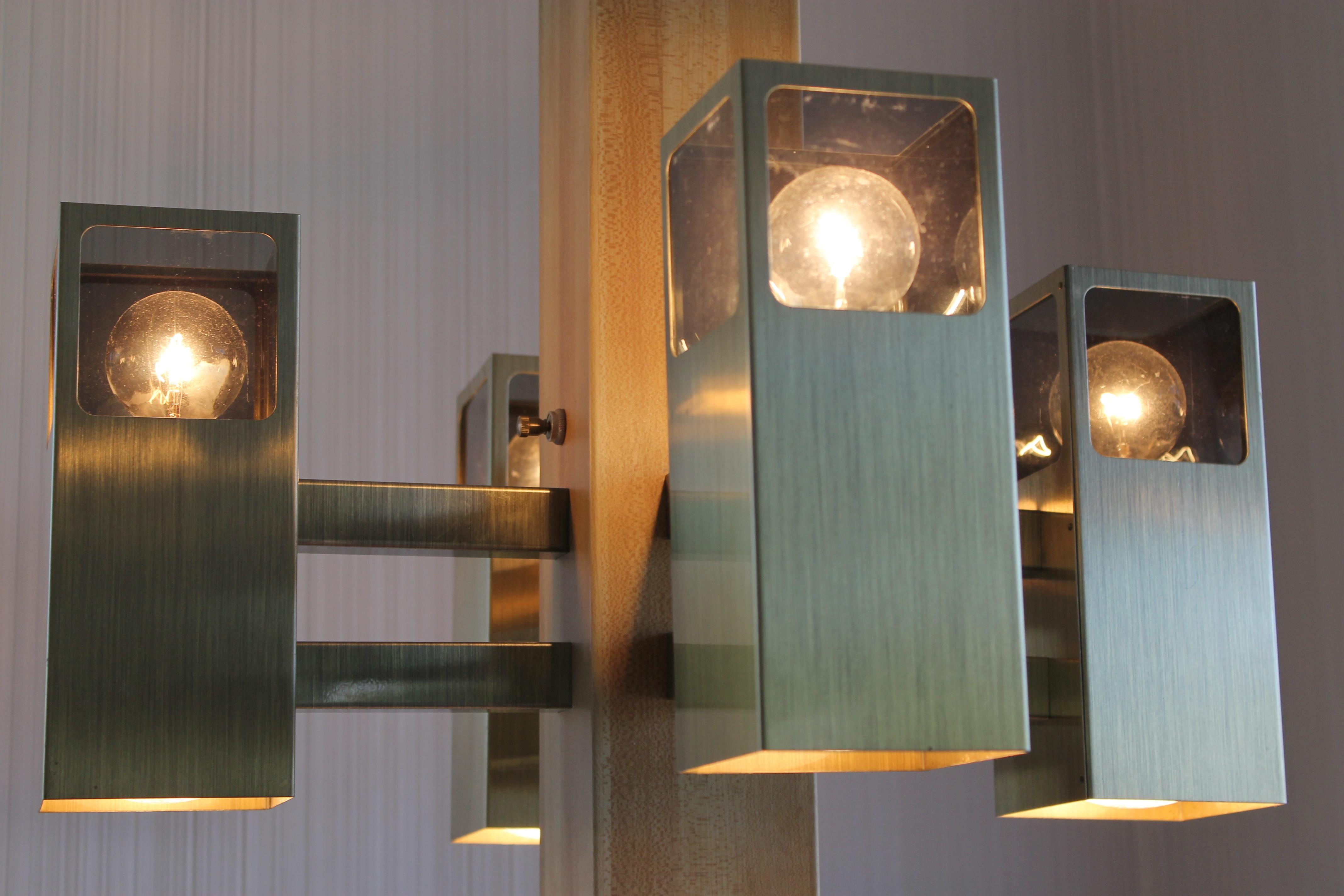 A circa 1960s modern chandelier with four square canisters radiating from a central square hub. Smoked grey plexiglass windows soften the light behind. The four canisters and the hub all have a spot aiming down from within. The three-way switch