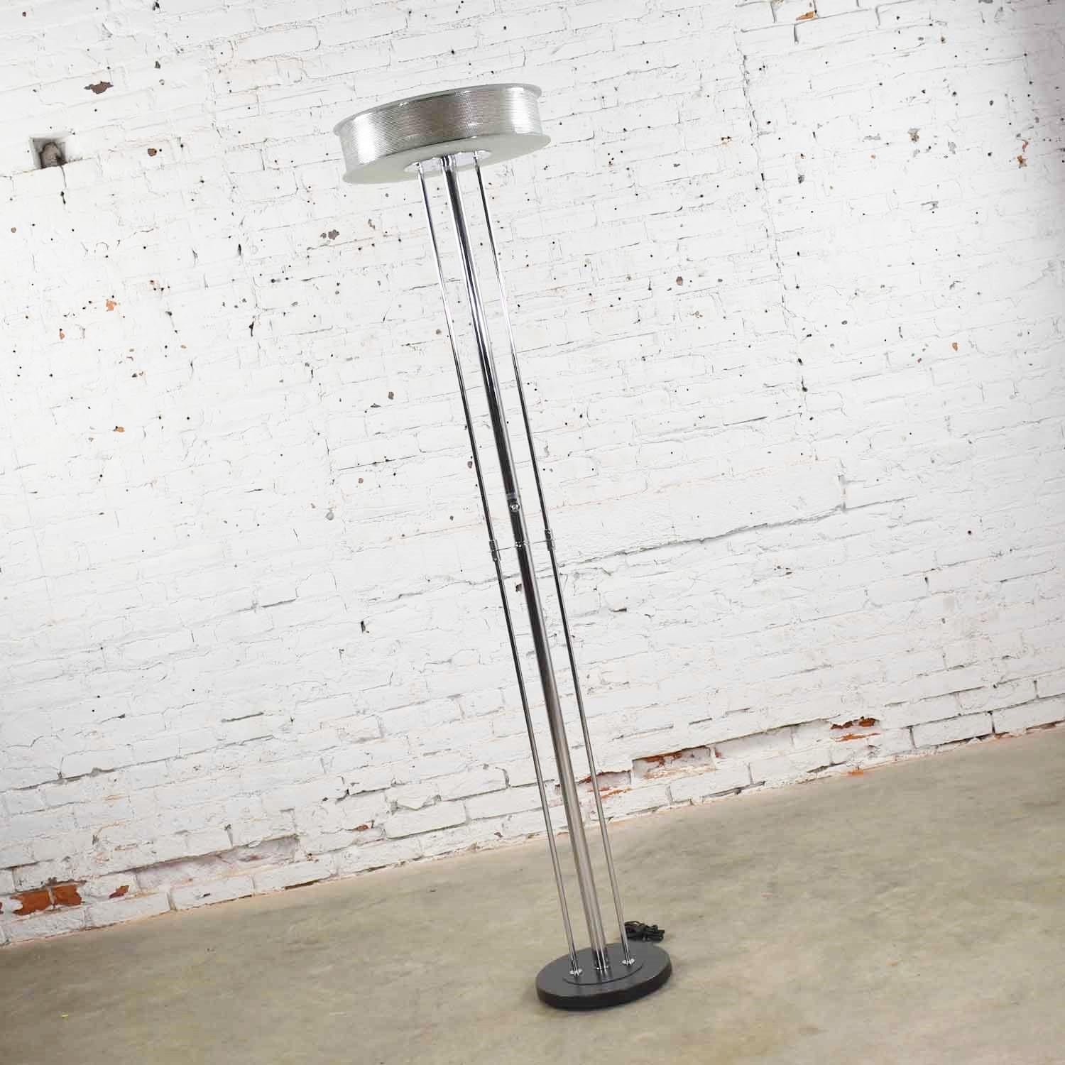 Handsome modern chrome floor lamp with a triple shaft and round perforated ring and glass disc shade. It is in wonderful vintage condition. The chrome on the shafts and upper portions of the lamp are in fabulous shape as are the metal and glass.