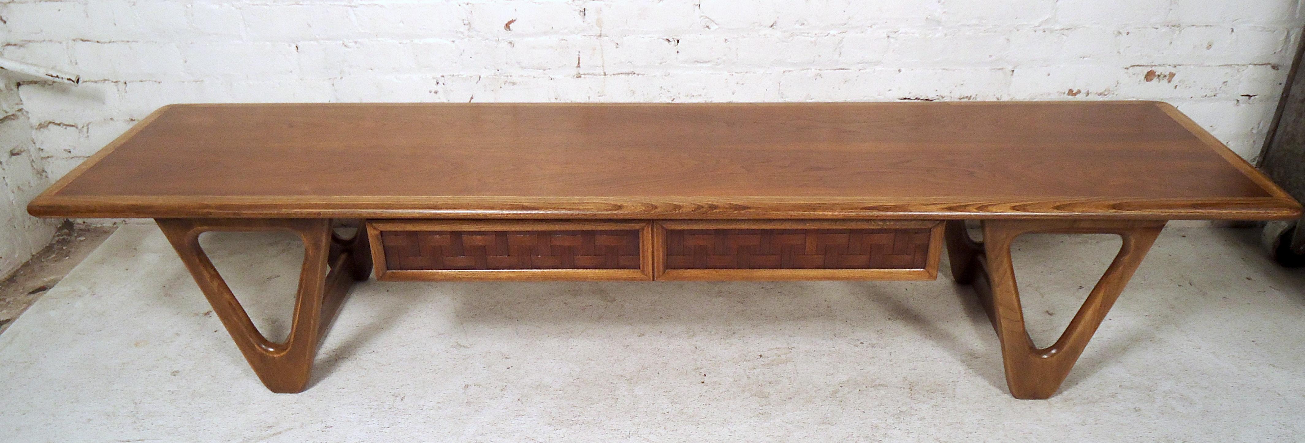 Stilvoller Couchtisch der Lane Furniture Company aus der Jahrhundertmitte, ca. 1960er Jahre. Großzügige Tischfläche, einzigartig geformte Beine, eine Schublade unter der Tischplatte mit einem interessanten Webmuster auf der Schubladenfront.
Bitte