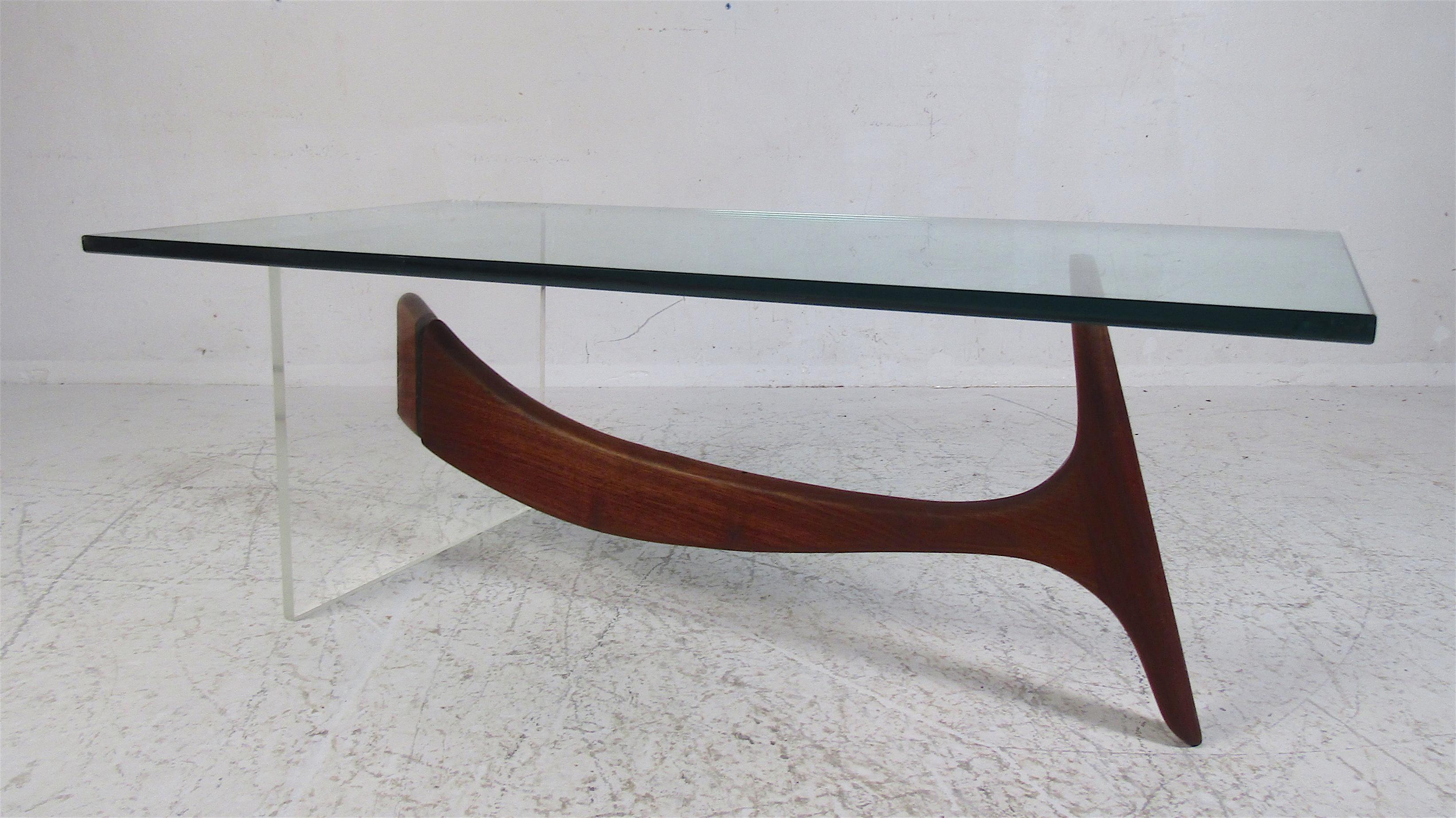 A stunning Mid-Century Modern coffee table that boasts a walnut and Lucite base. The two-tone design is sure to make a lasting impression in any modern interior. The impressive one-inch thick glass top offers plenty of space for setting items. A