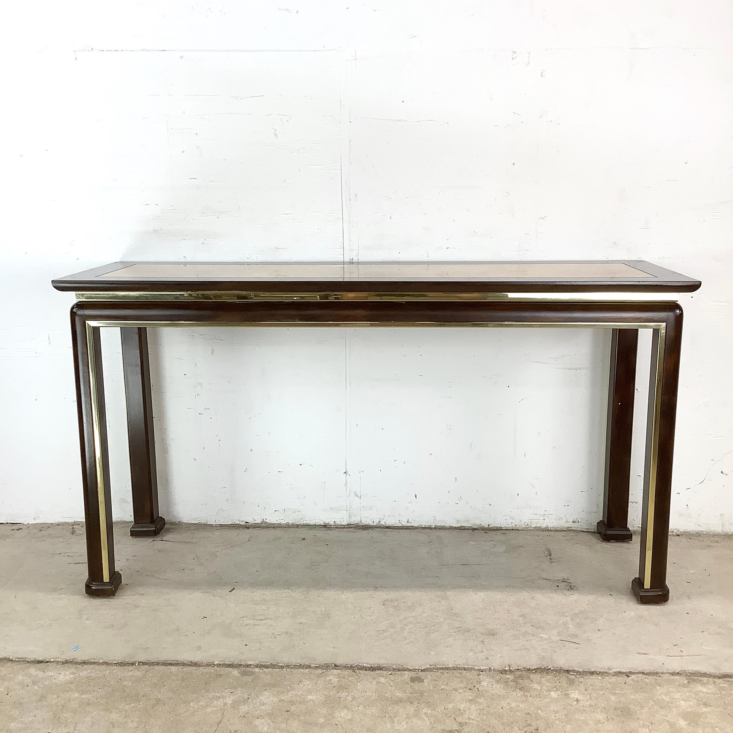 This finely constructed vintage console table showcases the bold elegance of late 1970s and early 1980s modernist design. The tabletop features a richly figured burled wood veneer inset, framed by a lacquered or ebonized wood border. The warm tonal