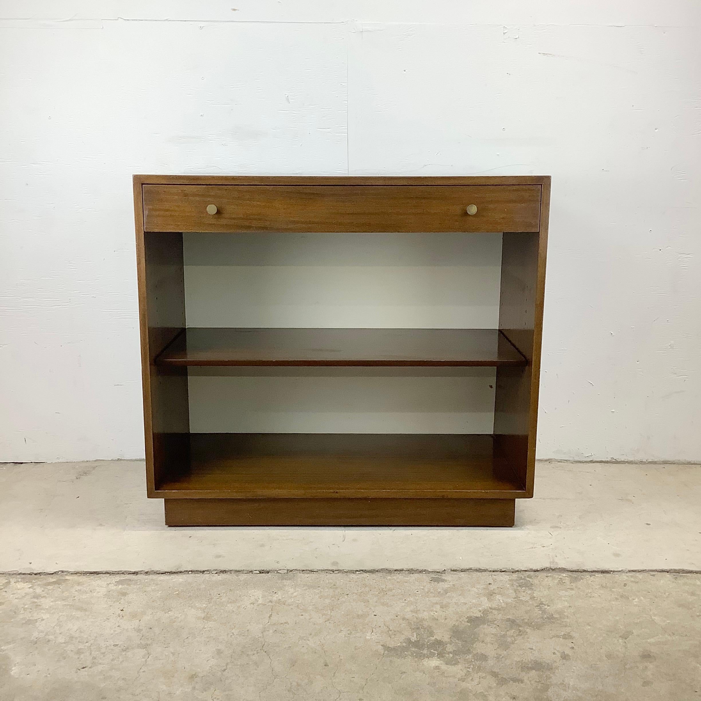 This striking Mid-Century Modern cabinet features a dark wood finish with adjustable shelf lower cubby and wide upper drawer with drop front. Unique storage piece for use in any setting but would be conducive to use as a media credenza or for office