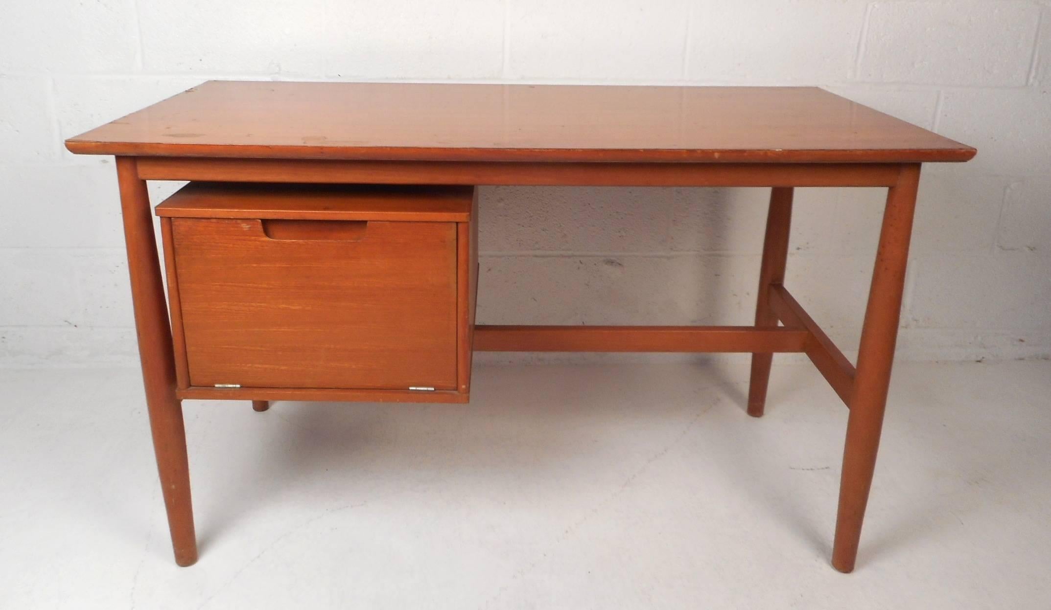 This stylish Mid-Century Modern desk features a drop down door that hides two drawers and two small compartments. Quality craftsmanship with a finished back and a stretcher for added sturdiness. This fabulous case piece provides plenty of work space