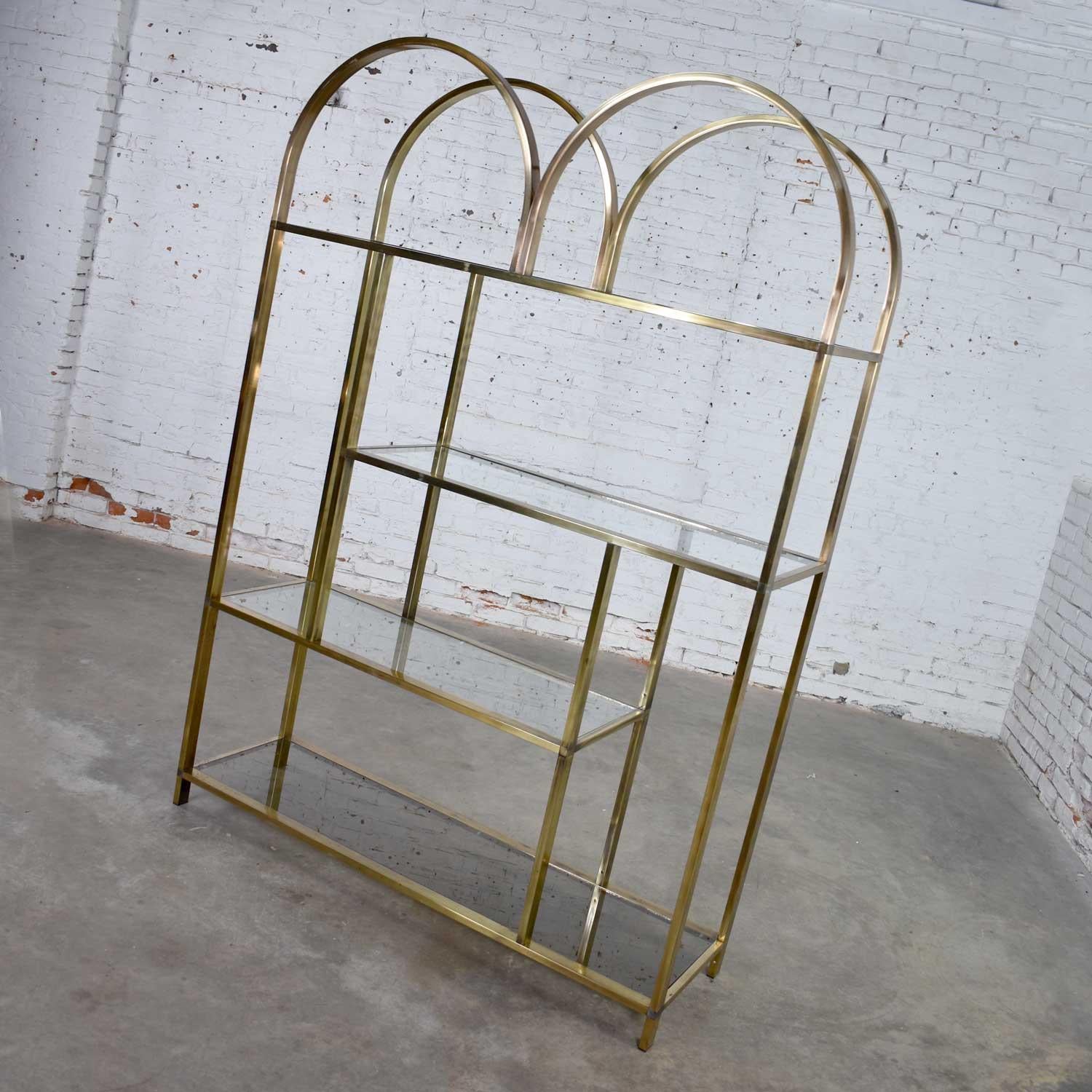 Handsome brass plated chrome modern double arched étagère or display shelves. The bottom shelf is smoked glass and the others are clear. It is in wonderful vintage condition. The brass plating is distressed and worn in several places giving a very