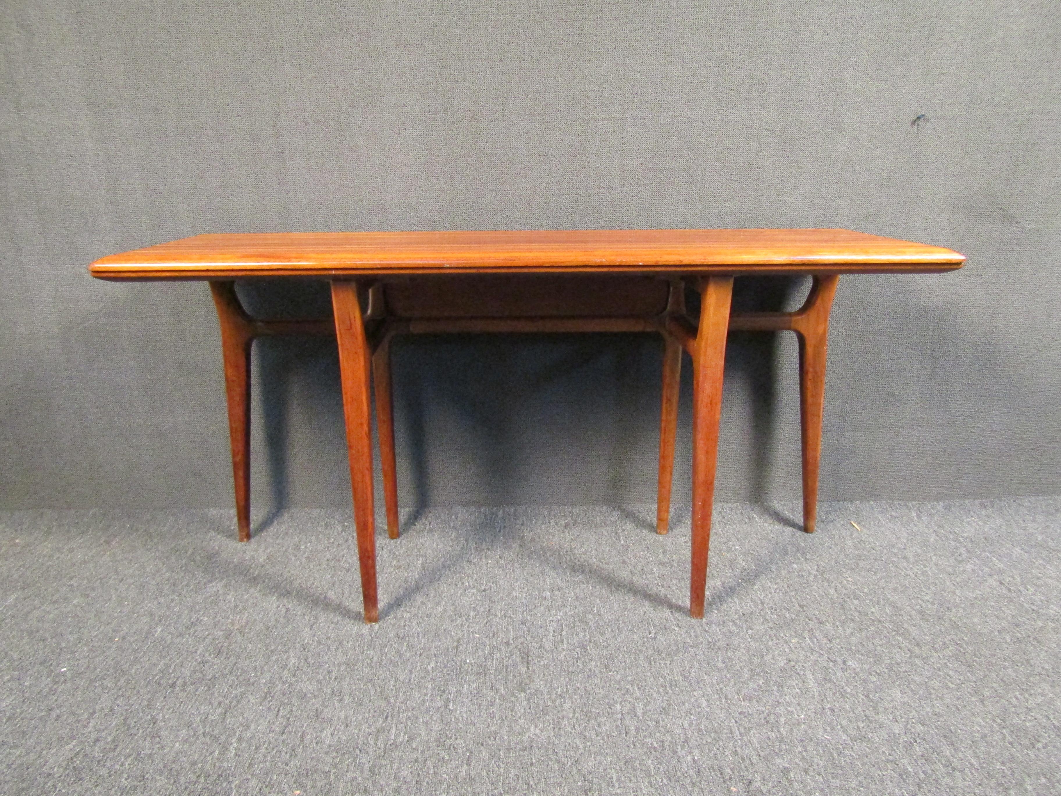 This gorgeous Mid-Century Modern console table folds out into a dining table, making it perfect for entertaining and easy to store as a hall table or side table. This table features sculpted legs and stunning wood grain. Perfect for any home or