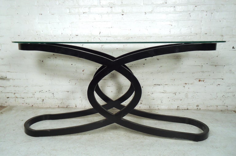 This elegant vintage modern console table makes the perfect addition to any entryway, hallway, or behind the sofa. A uniquely designed black metal base and glass top, this stylish midcentury hall table is sure to add style and grace to any setting.